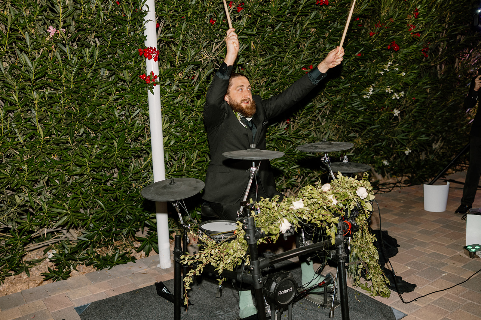 The groom passionately plays a drum set decorated with florals, bringing energy to the reception.