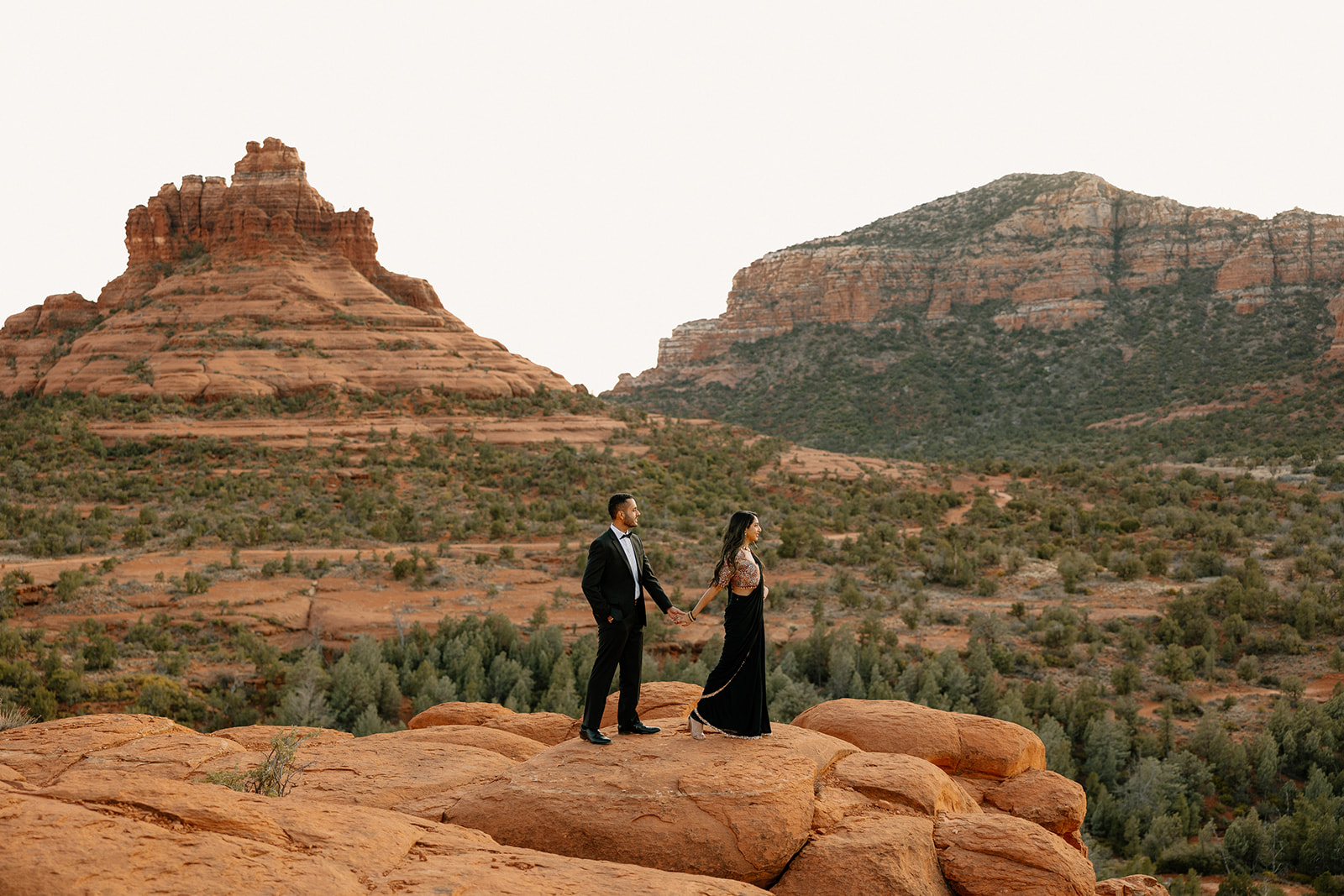 With red rocks in every direction, the couple holds hands and looks out over the landscape during their Sedona elopement.