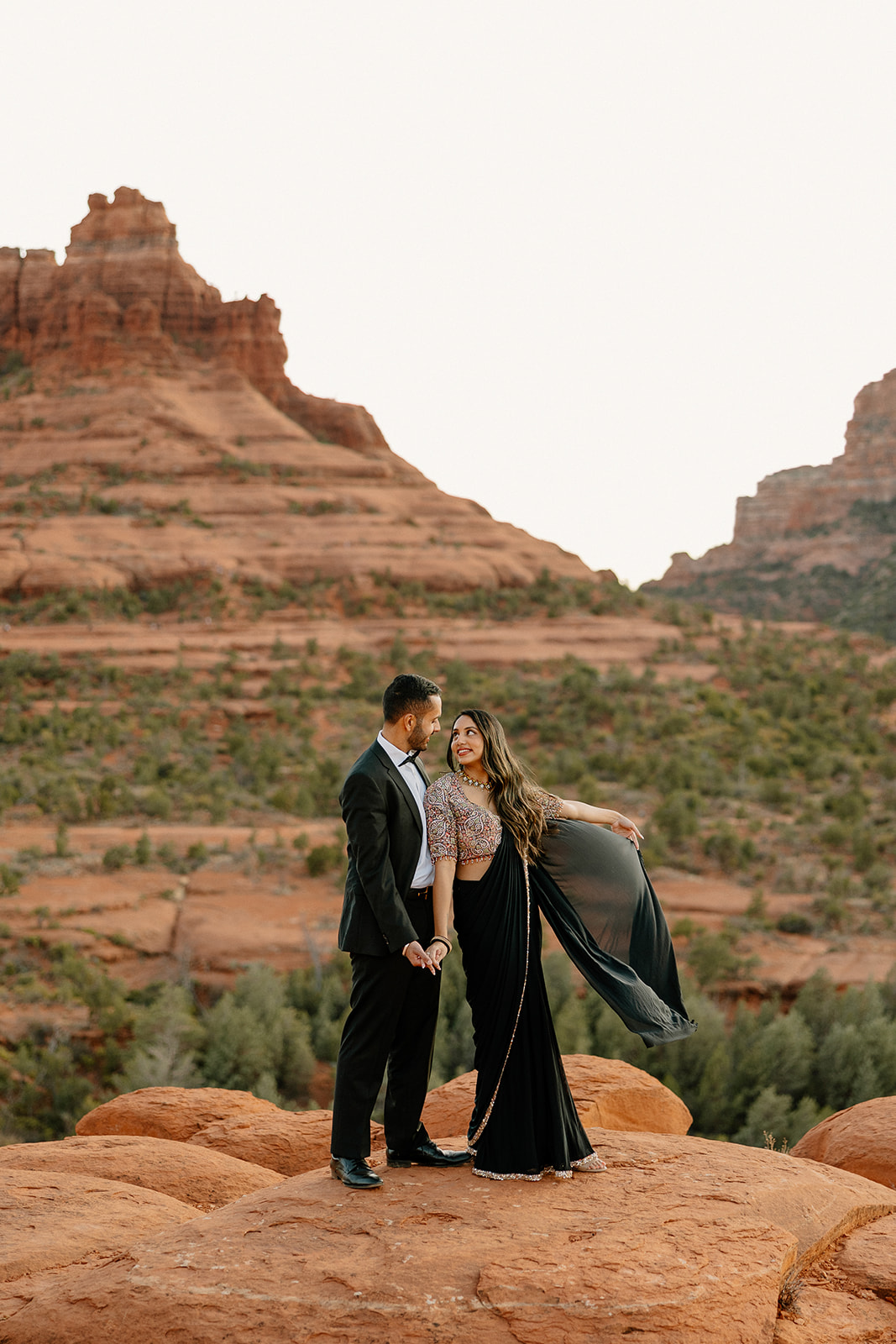 Dressed in formalwear, the couple shares a romantic moment with windswept fabric trailing behind them in Sedona.