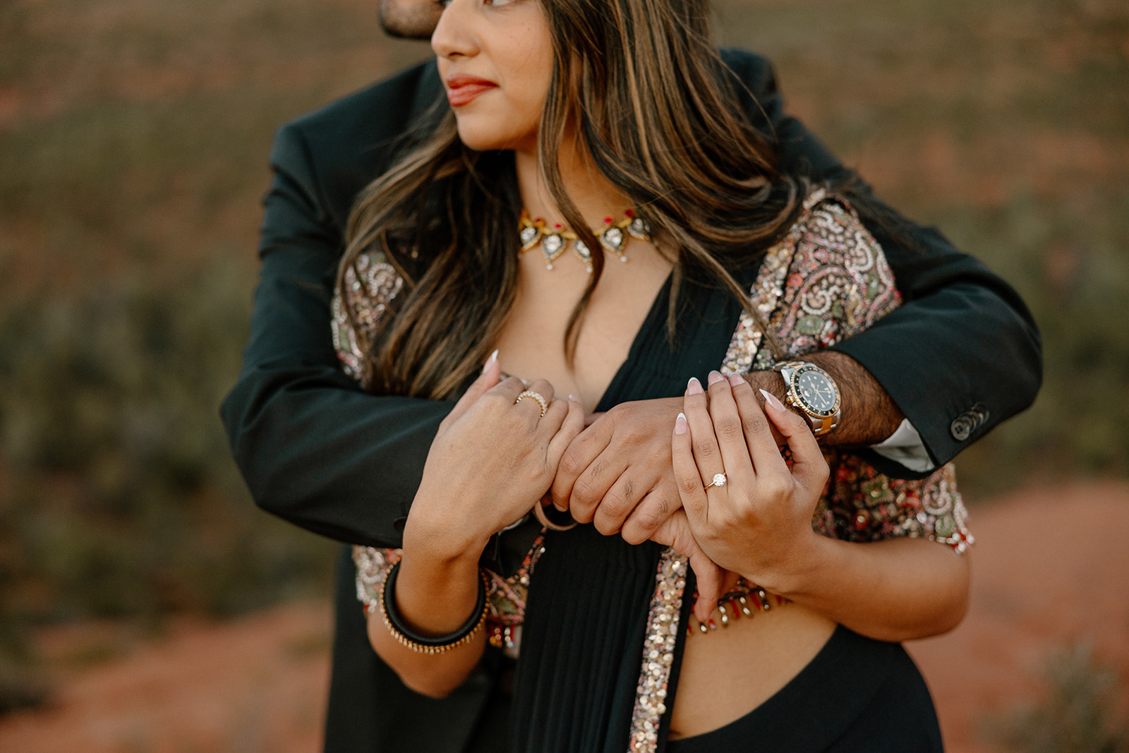 Close up of couple embracing showcasing woman's engagement ring