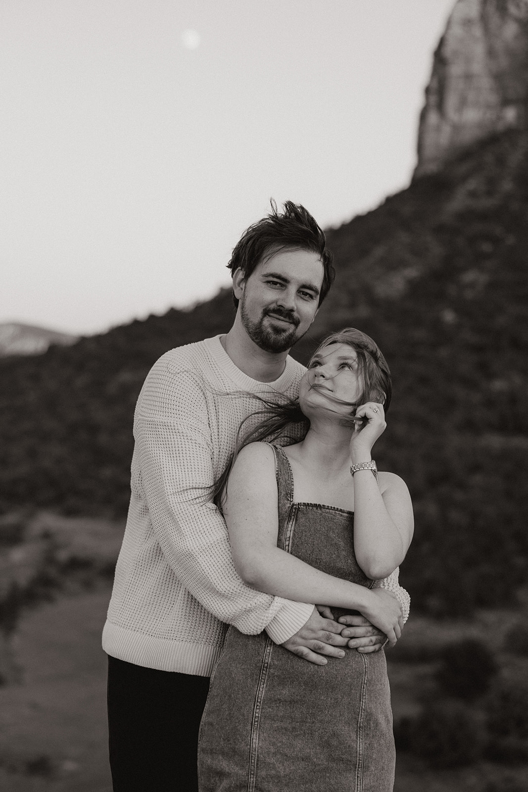 In a grainy black-and-white moment, he wraps her up as she glances up with wind in her hair.