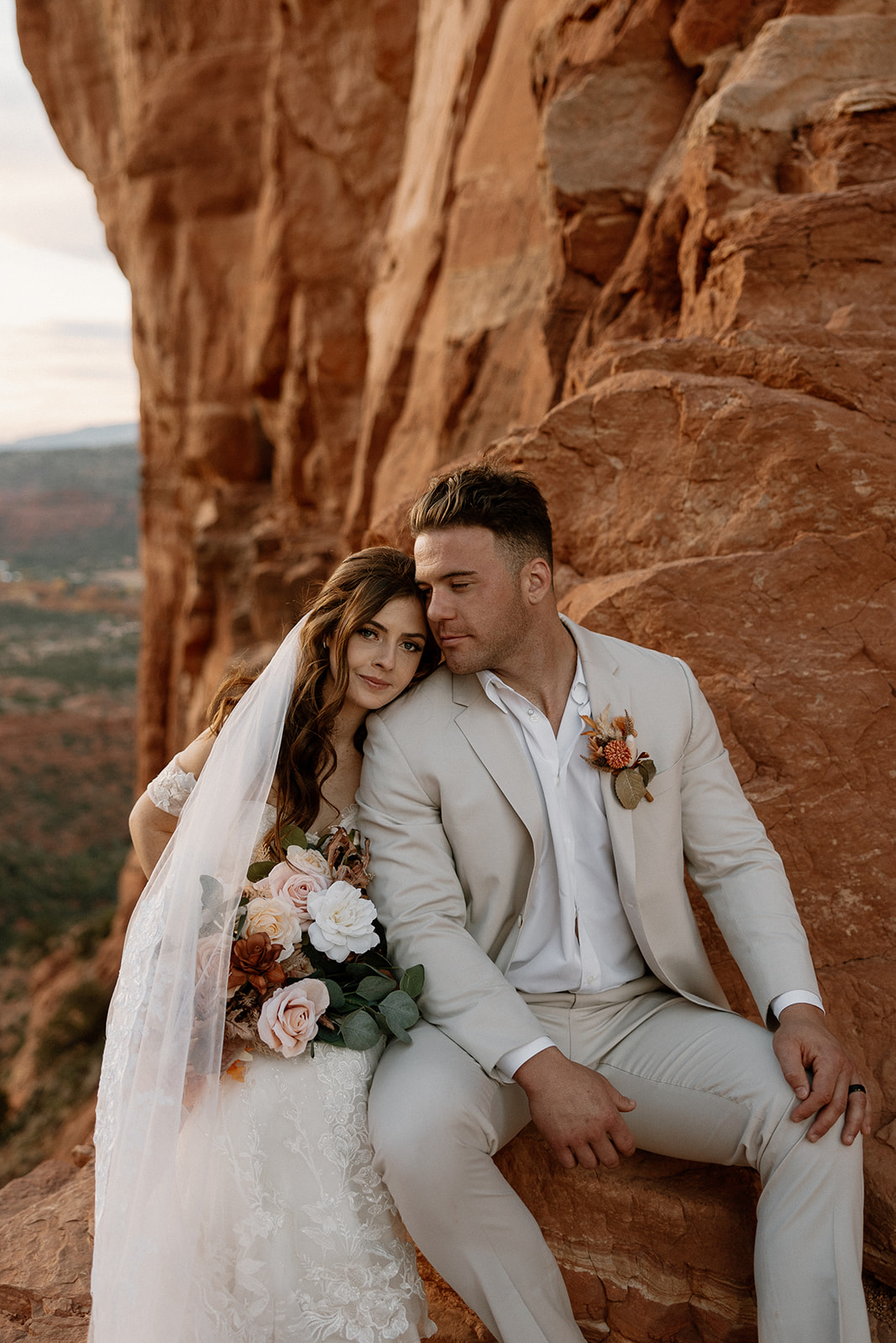 Newly married couple sitting together with bride's head on groom's shoulder