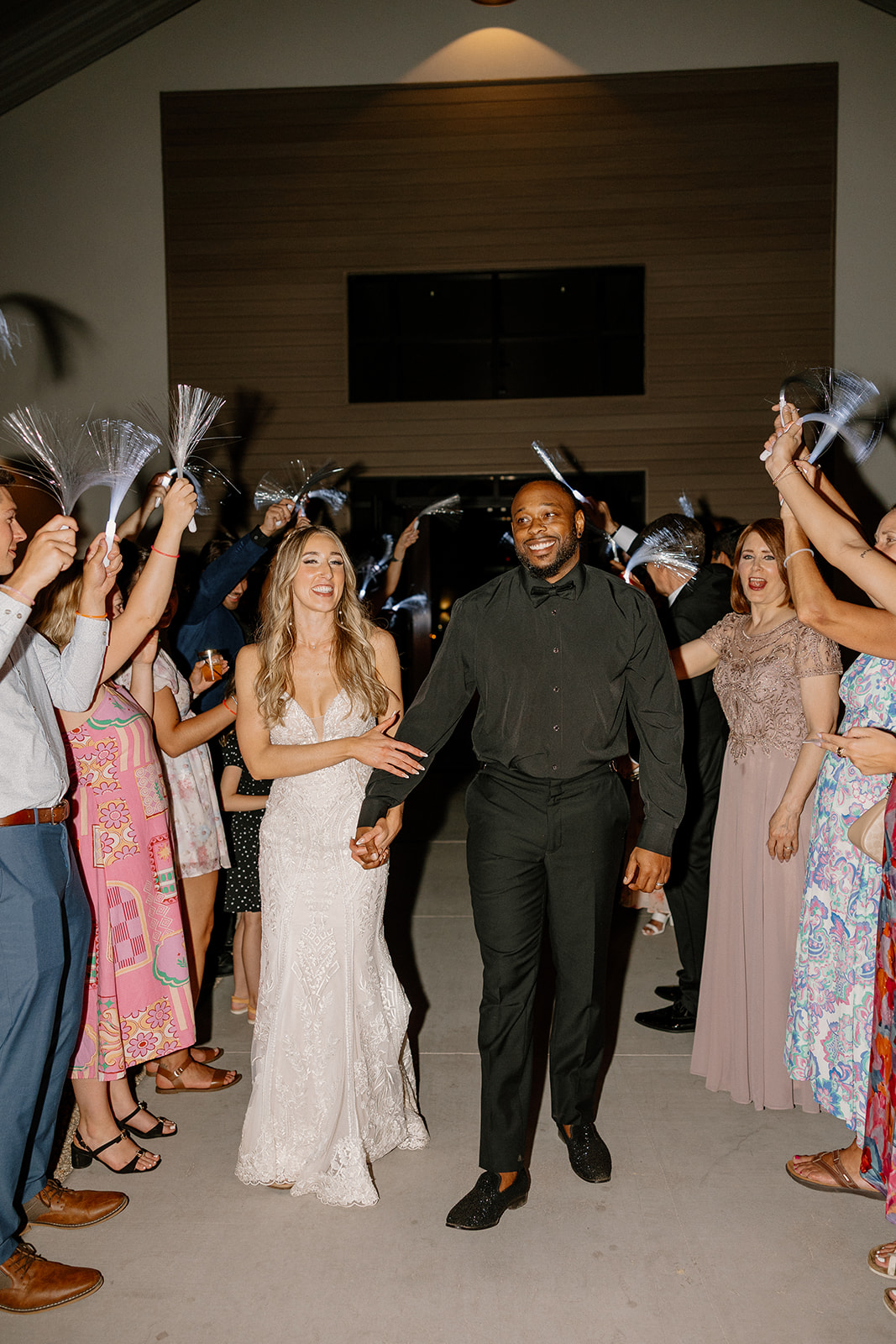 Beaming with joy, the couple walks hand-in-hand through a tunnel of cheering guests—an unforgettable moment from their desert view weddings day.