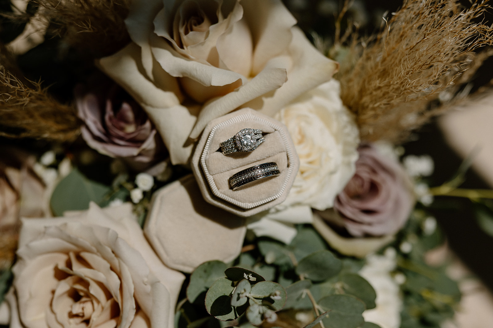 Wedding rings sitting in ivory ring box sitting on flowers 