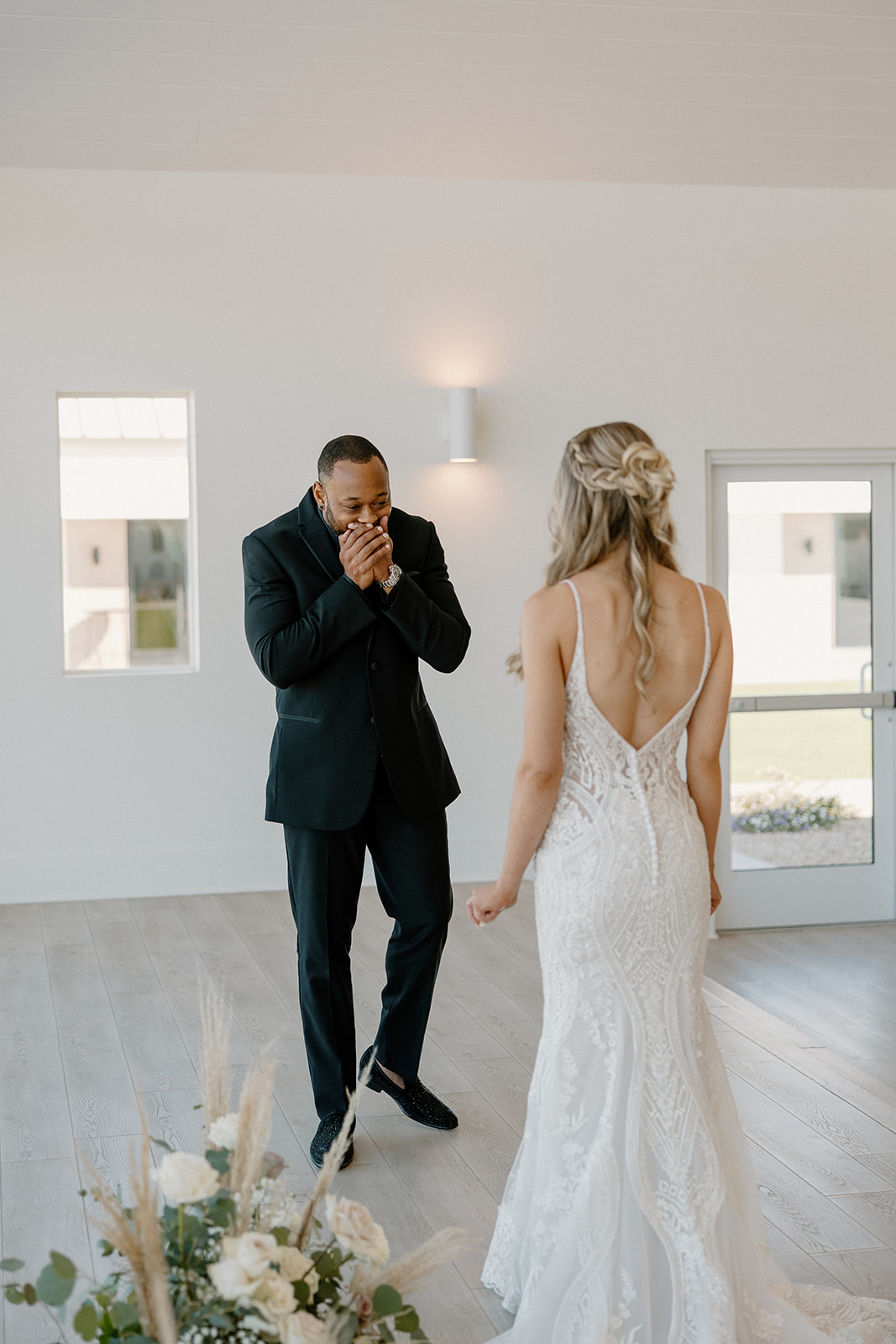 Hands to his face, the groom is visibly emotional as he sees his bride for the first time in her gown—a raw, beautiful moment.