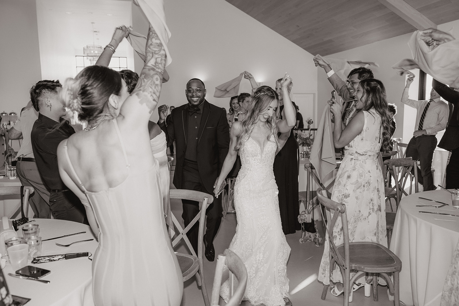 Guests wave napkins and cheer as the bride and groom make their reception entrance, dancing their way into the celebration in true desert view weddings fashion.