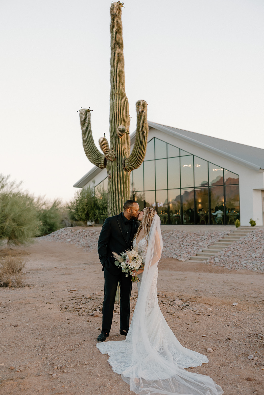 Newly married bride and groom kiss in front of a cactus after their intimate wedding ceremony 