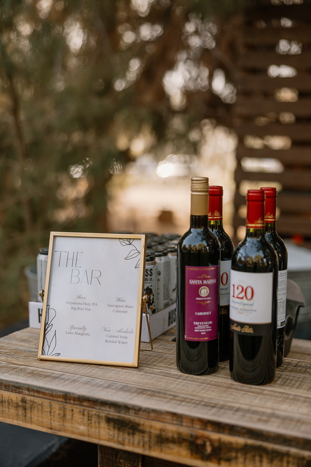 Bar menu set up with custom drink menu and bottles of wine next to it. 