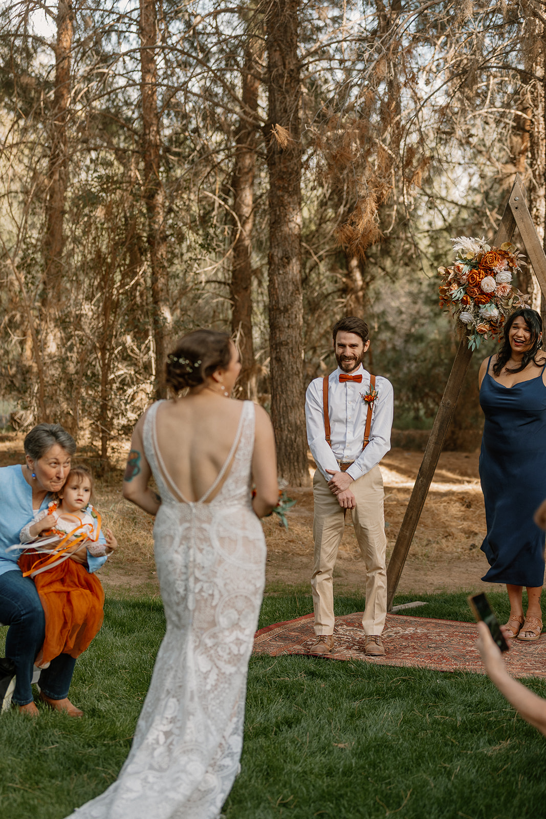 Groom lights up with a smile as he watches his bride walk toward him during their outdoor ceremony at Schnepf Farms.