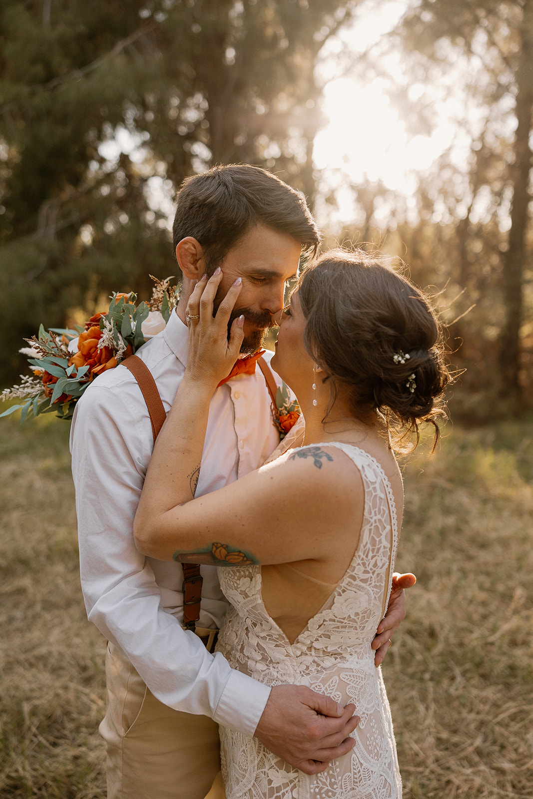  Bride gently touches her groom’s face during a quiet, romantic golden hour moment among the trees at Schnepf Farms.