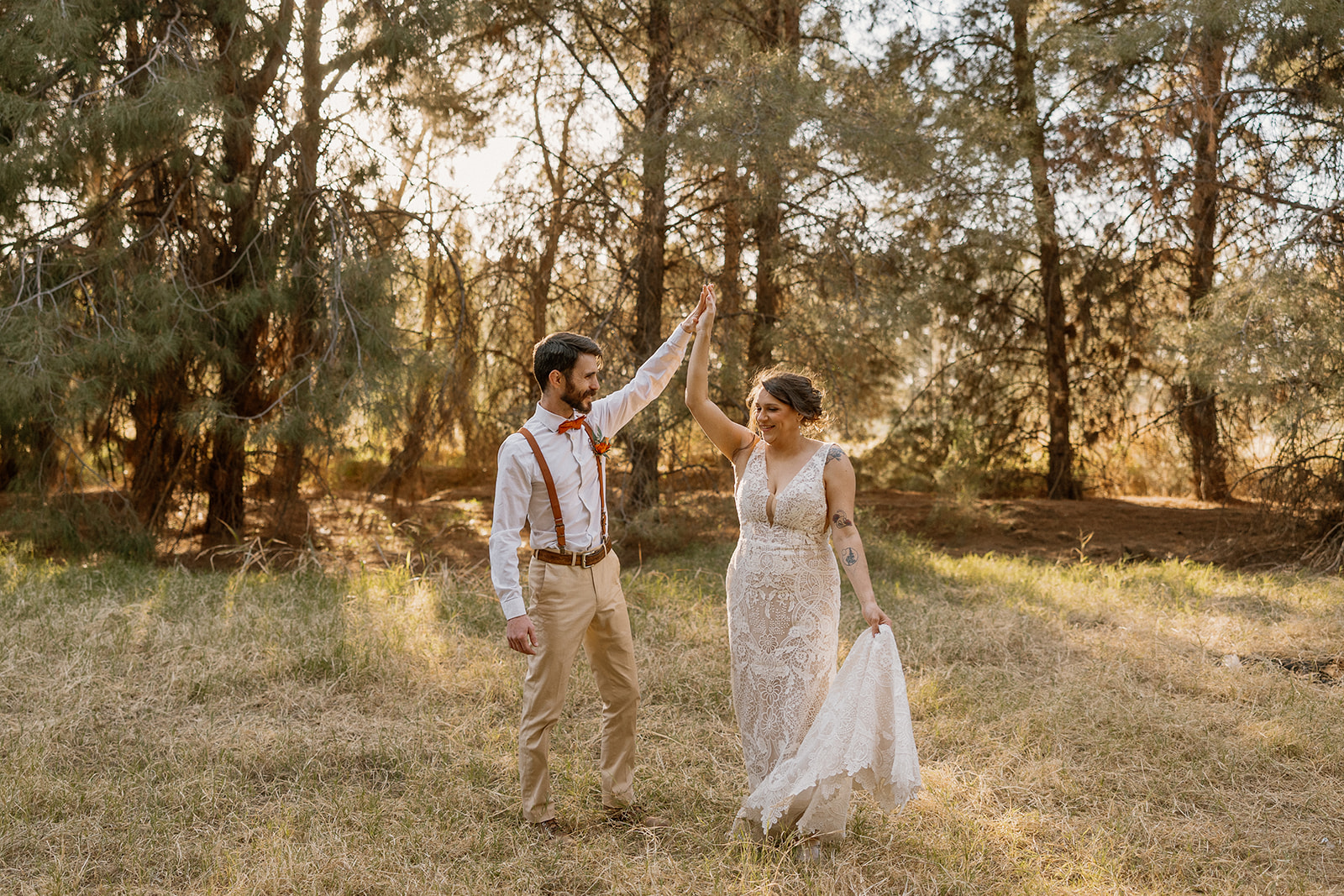 Newlyweds share a joyful high-five in the forested golden hour glow at Schnepf Farms.