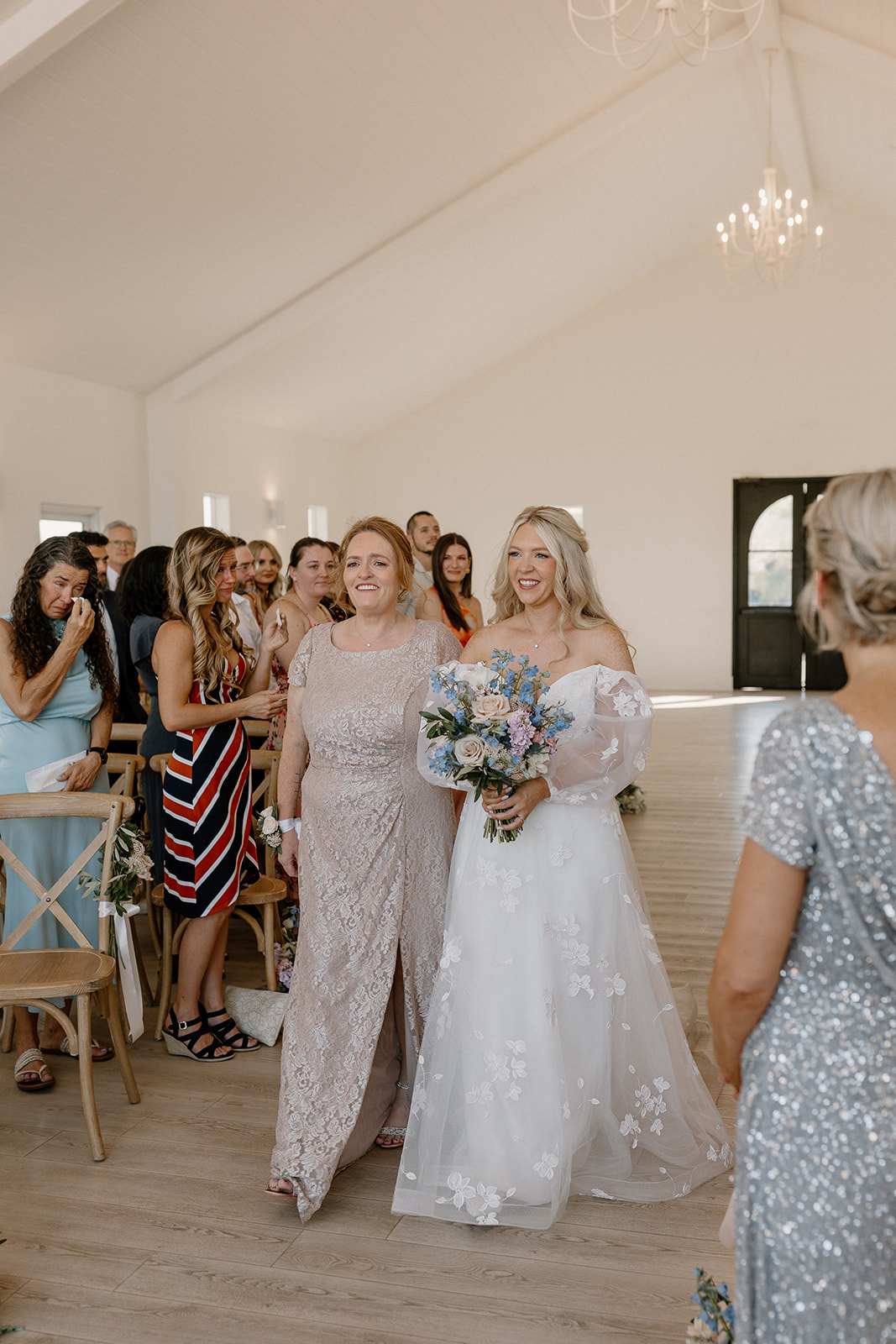 Bride walks down the aisle with beautiful bridal bouquet in hand as mother walks her down the aisle. 