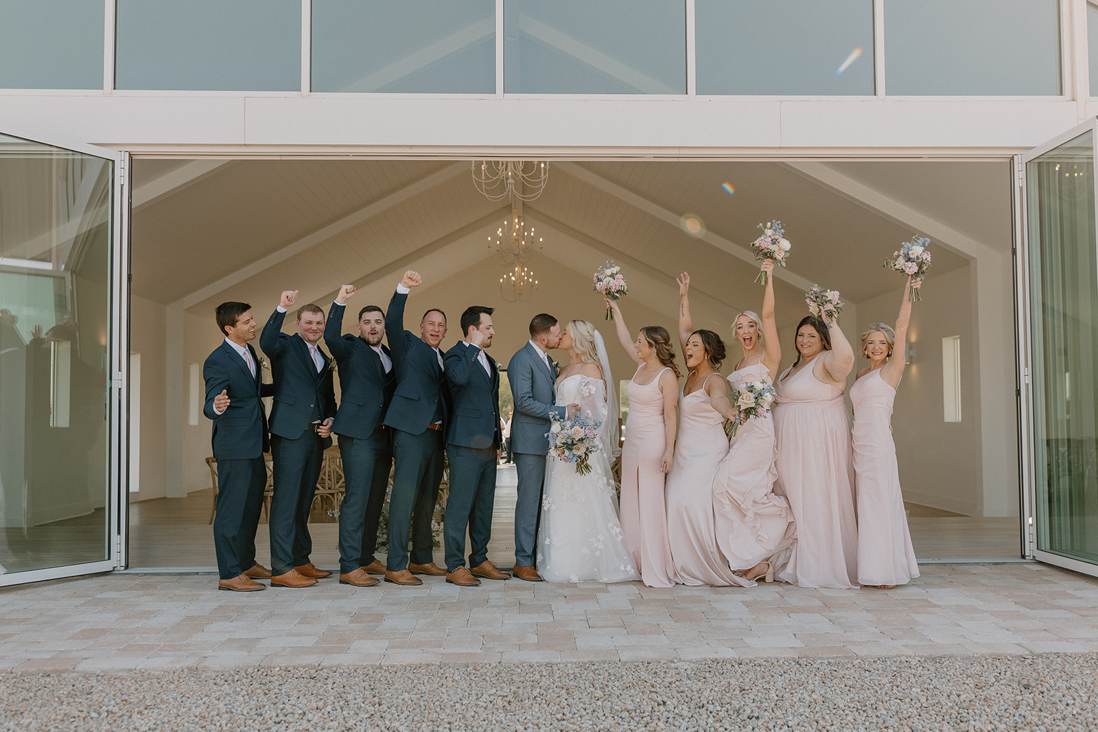 Bride and groom kiss and wedding party celebrates them after Desert View wedding. 
