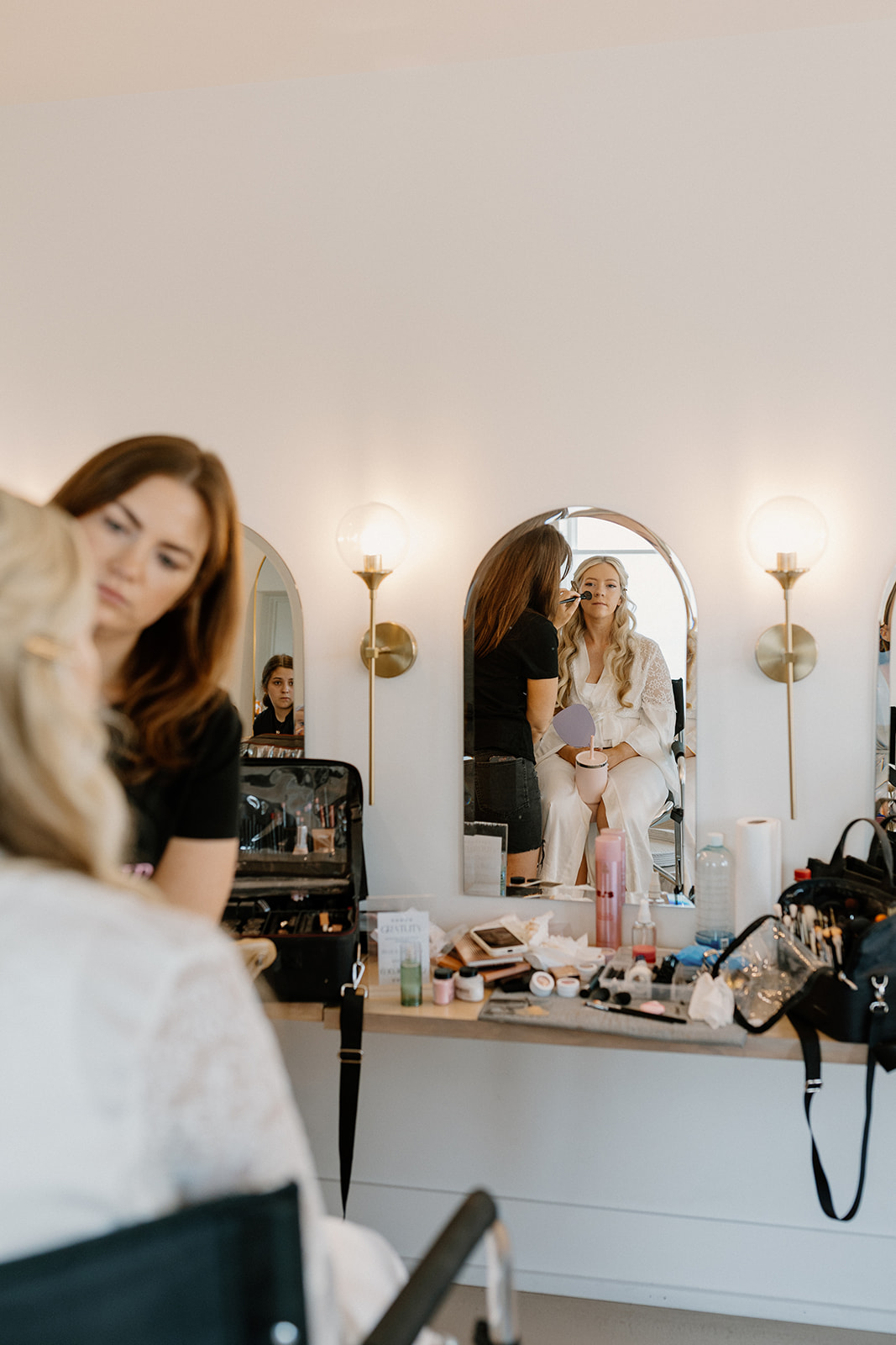 Bride getting makeup touch ups done by makeup artist before getting wedding dress on. 