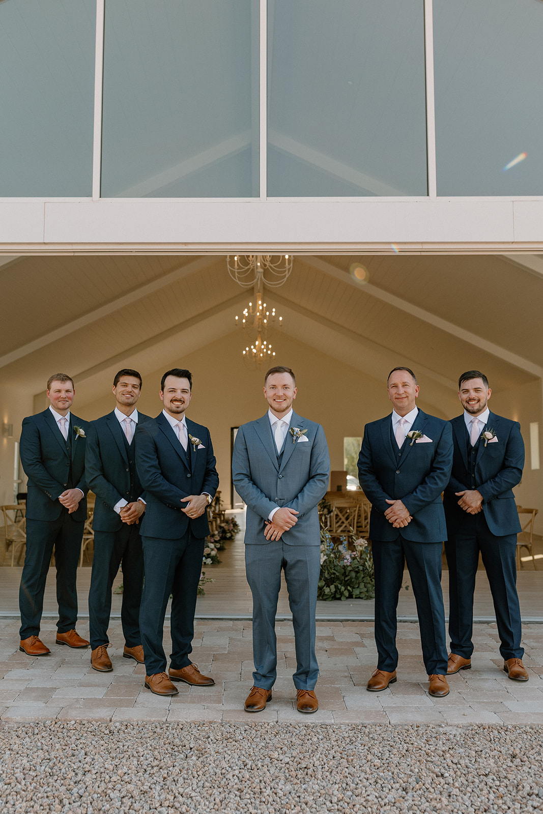 Groom and groomsmen stand together in navy suits smiling and celebrating. 