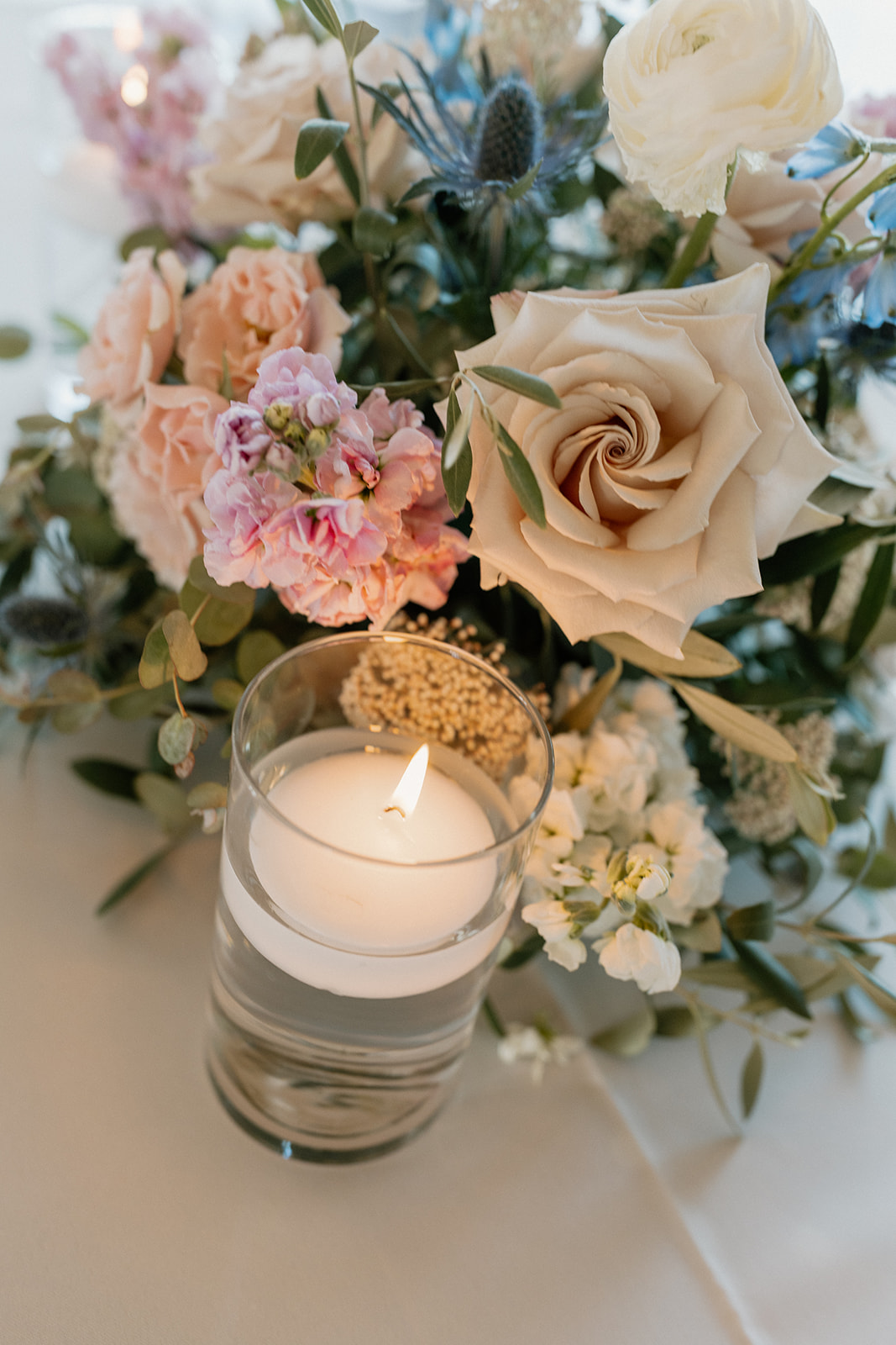 Candle lit centerpiece with beautiful floral arrangement behind the candle. 