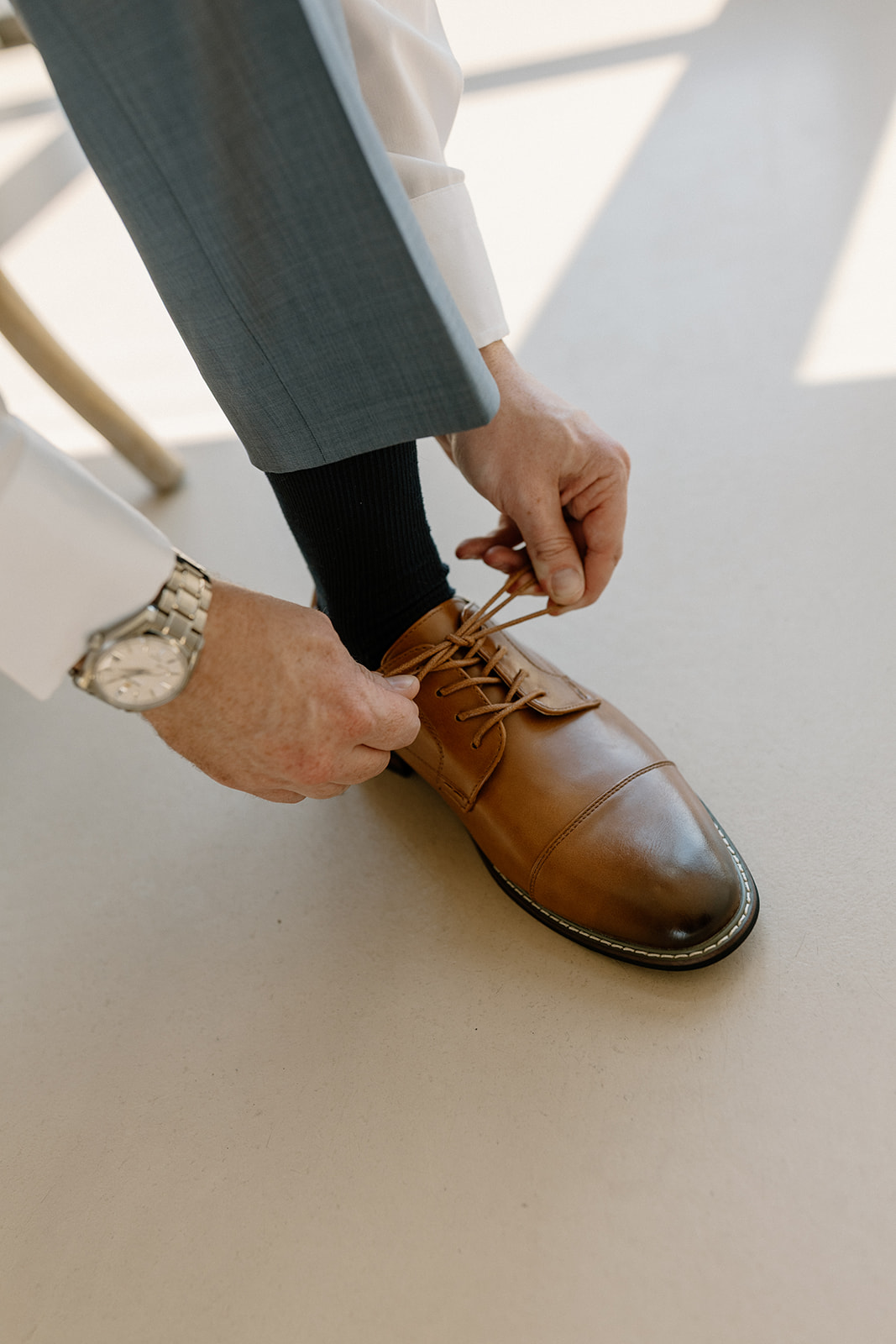 Groom tying brown dress shoes before intimate Desert View wedding. 