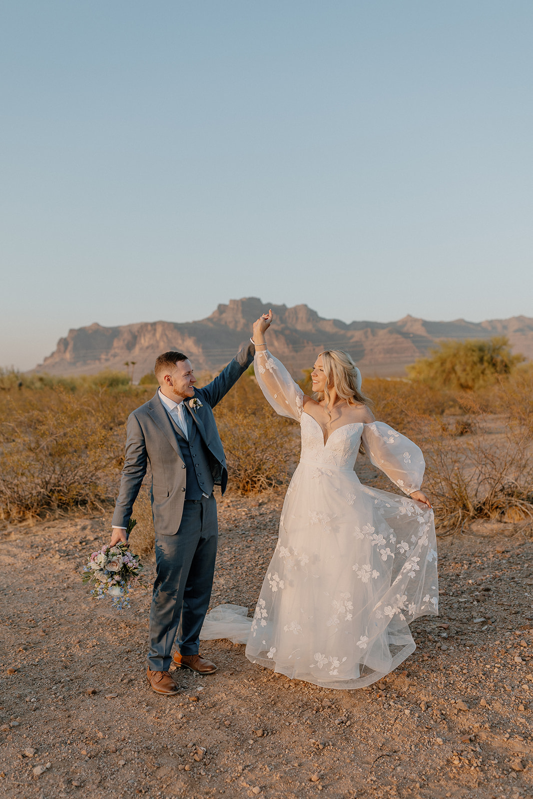 Groom spins bride and they dance together during outdoor bridal portraits. 