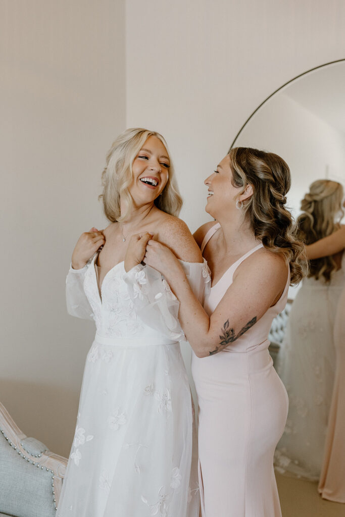 Bride and bridesmaid laugh together while getting ready for Desert View wedding. 