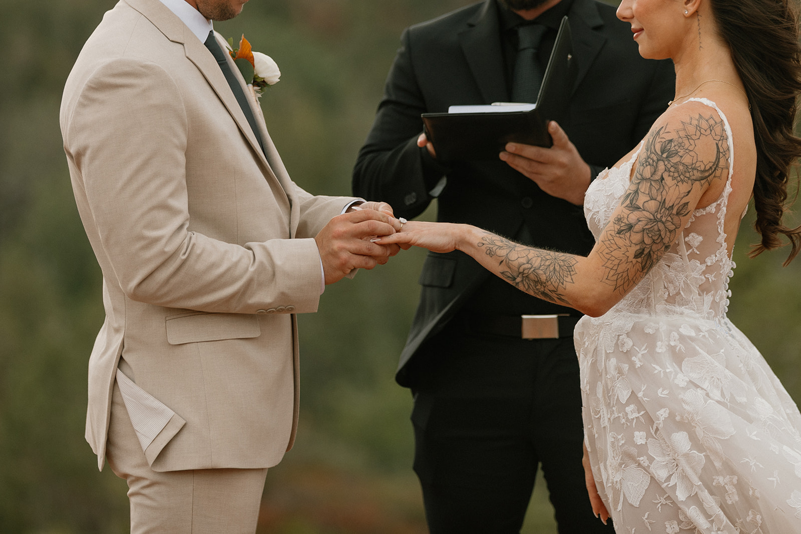Groom places the ring on his bride’s hand during their Bell Rock Sedona ceremony, both standing on natural sandstone with emotional focus.