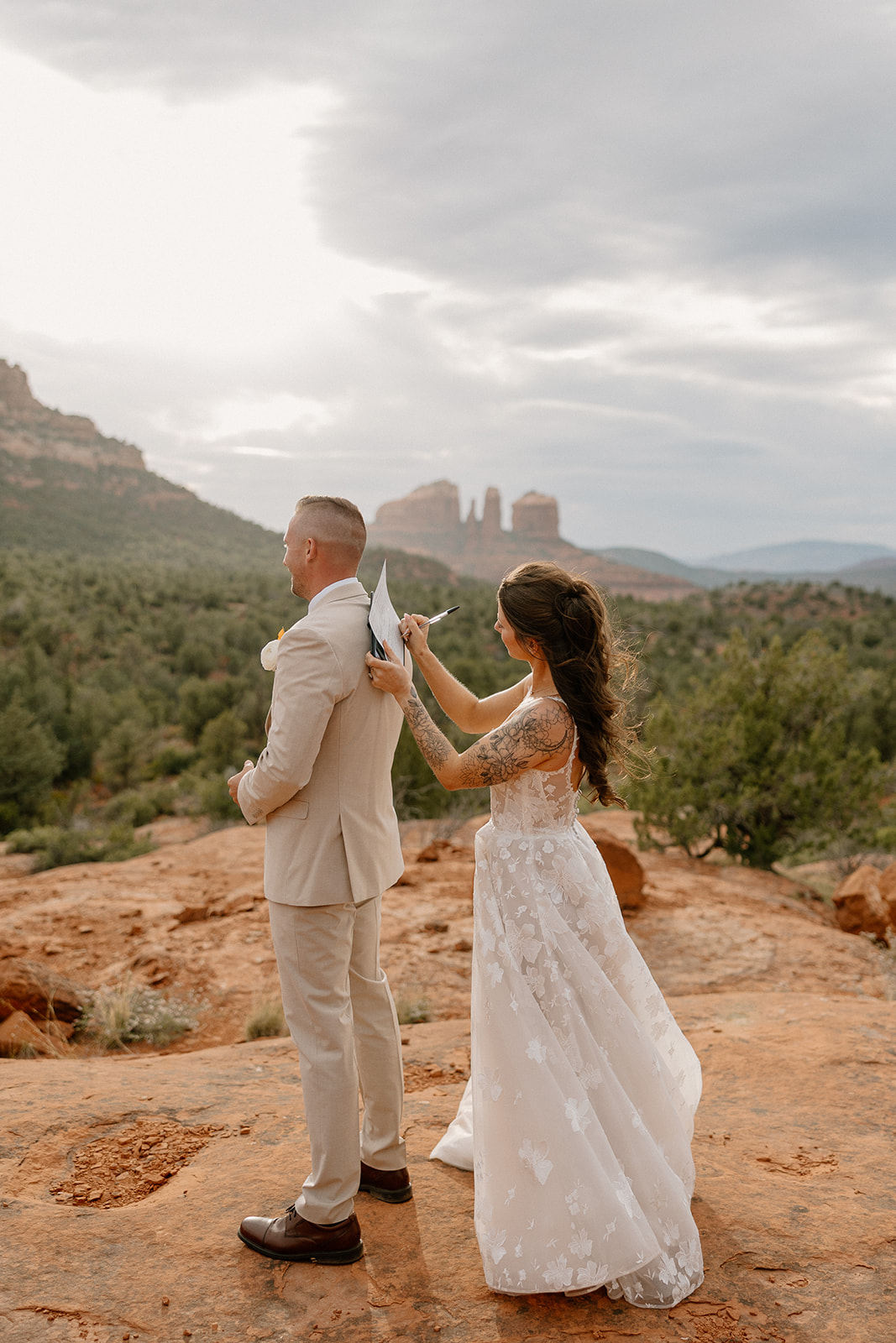 Bride signs marriage license using groom's back after their intimate elopement surrounded by family. 