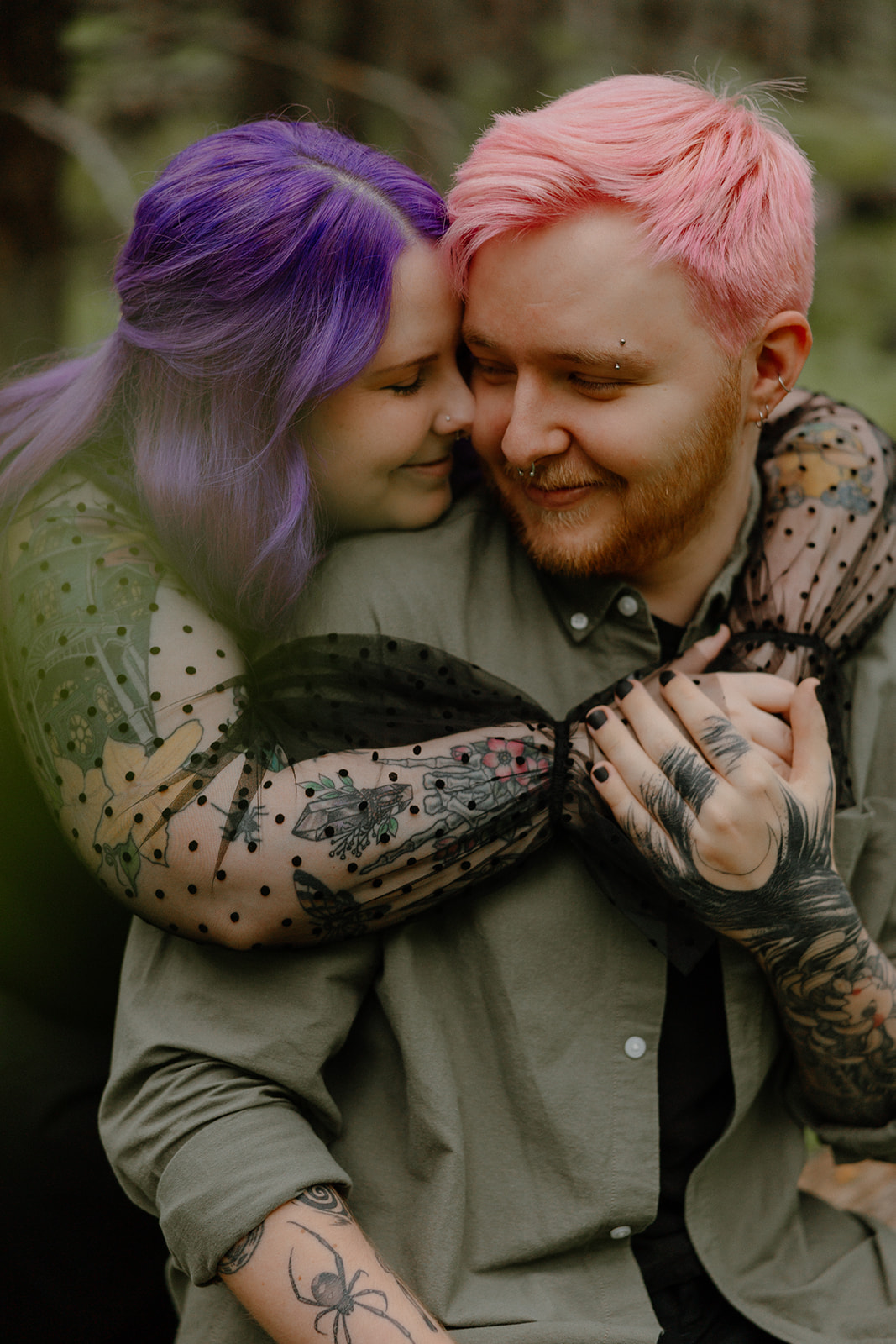 The woman wraps her arms around her partner from behind, both smiling with their faces close in a sweet candid shot.
