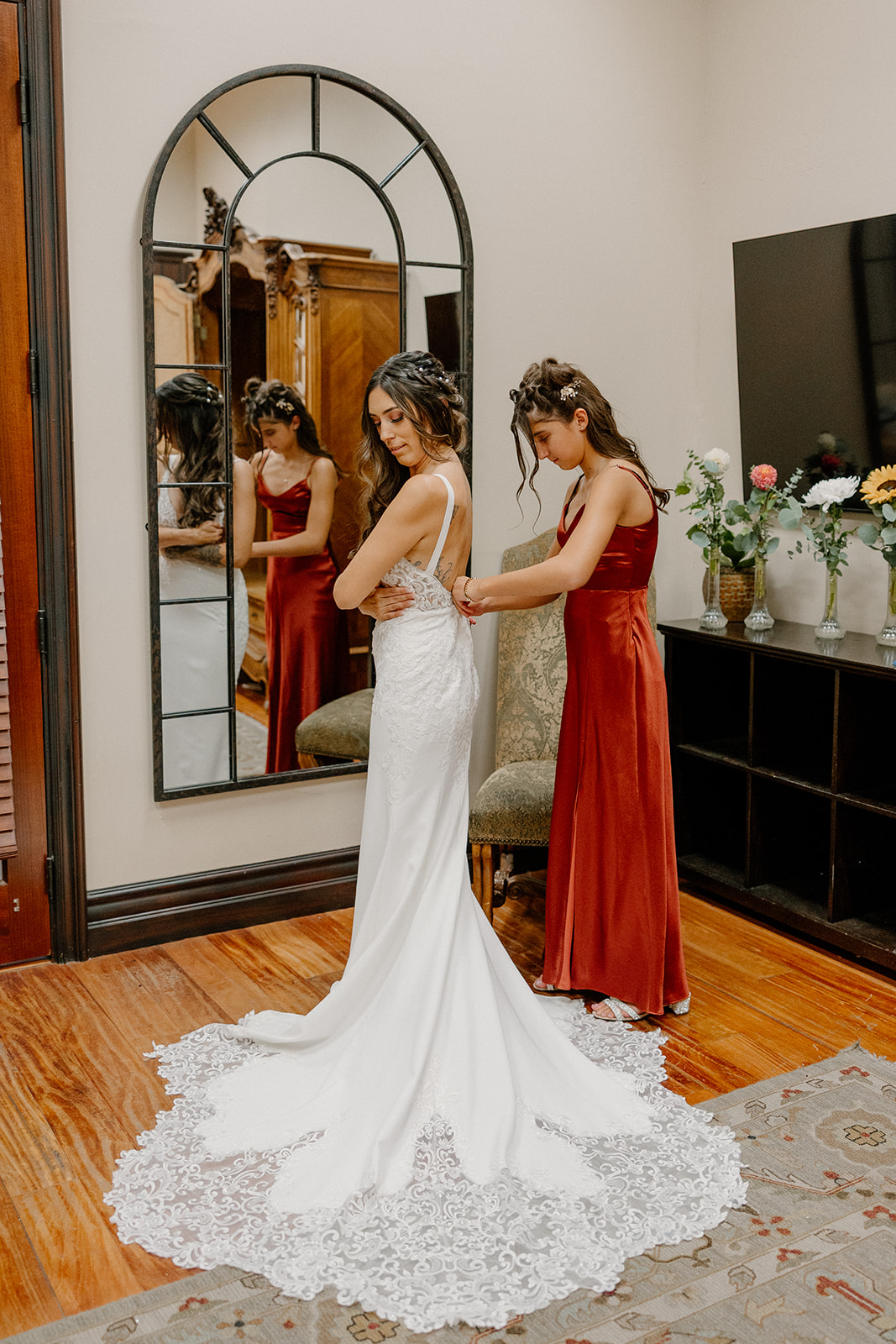 Bride standing alone in front of a mirror, showing off the full train of her gown in the bridal suite.