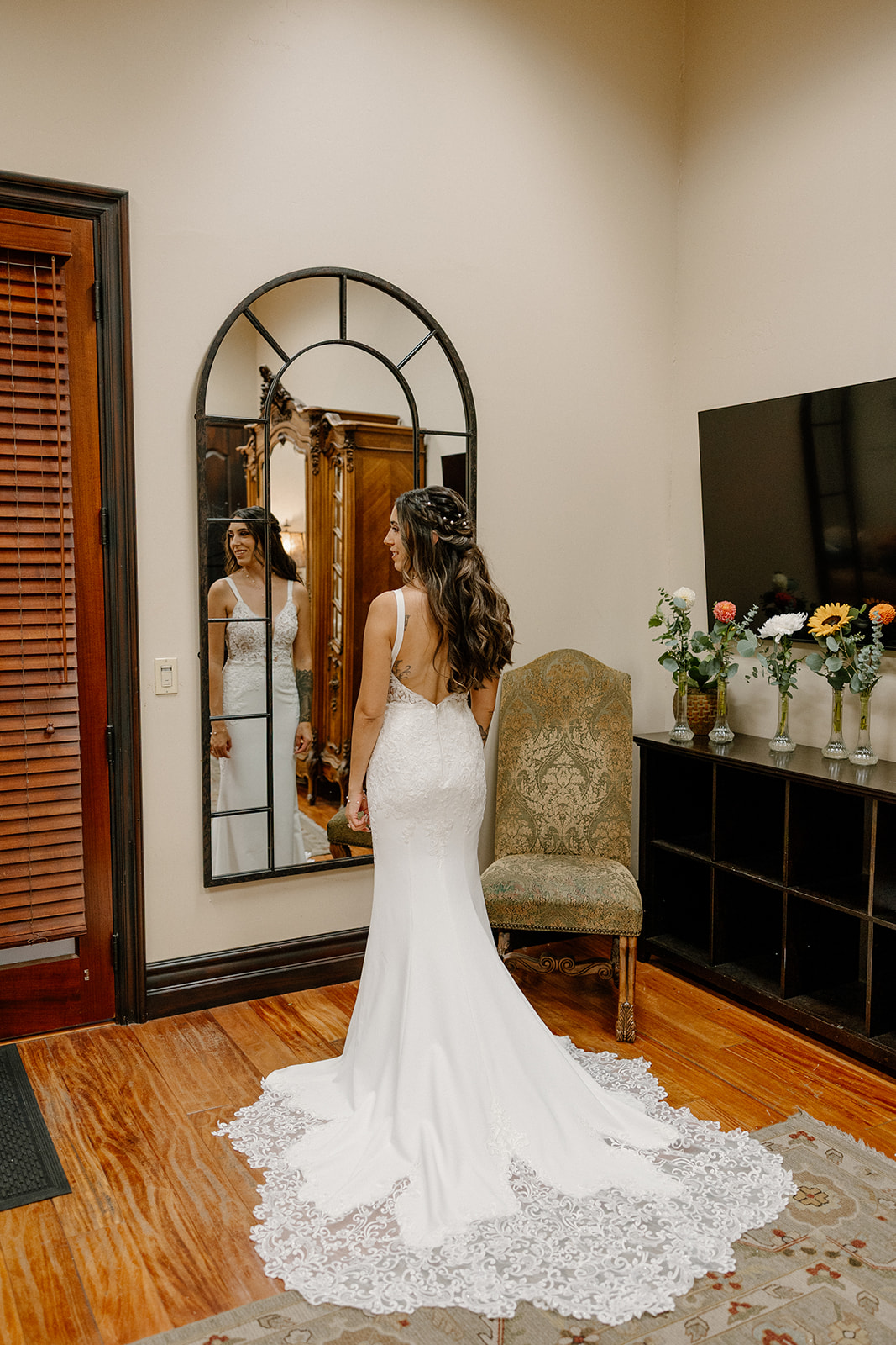 Bridesmaid helping the bride into her wedding dress inside a cozy getting-ready suite at a Gilbert wedding venue.