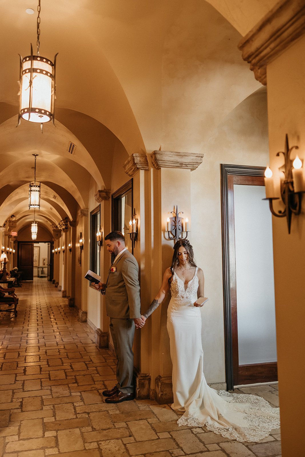 Bride and groom holding hands back-to-back for a quiet pre-ceremony moment inside a romantic Gilbert wedding venue.