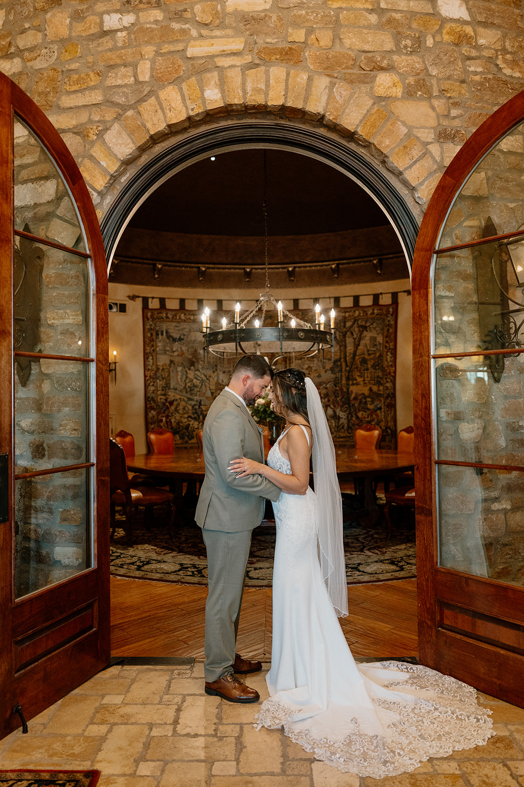 Bride and groom sharing a quiet moment under stone archway inside an old-world inspired room at a Gilbert wedding venue.