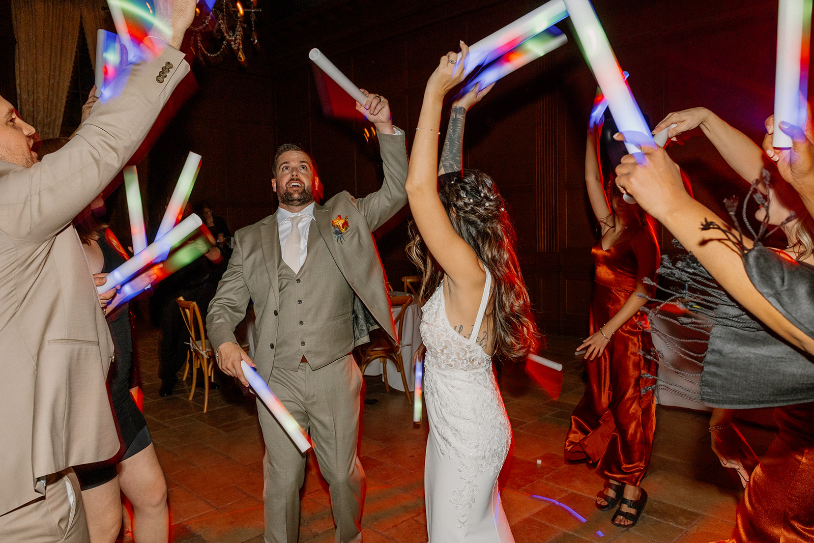 Surrounded by friends and family, the couple dances under colorful lights with glow sticks flying and champagne energy in the air.