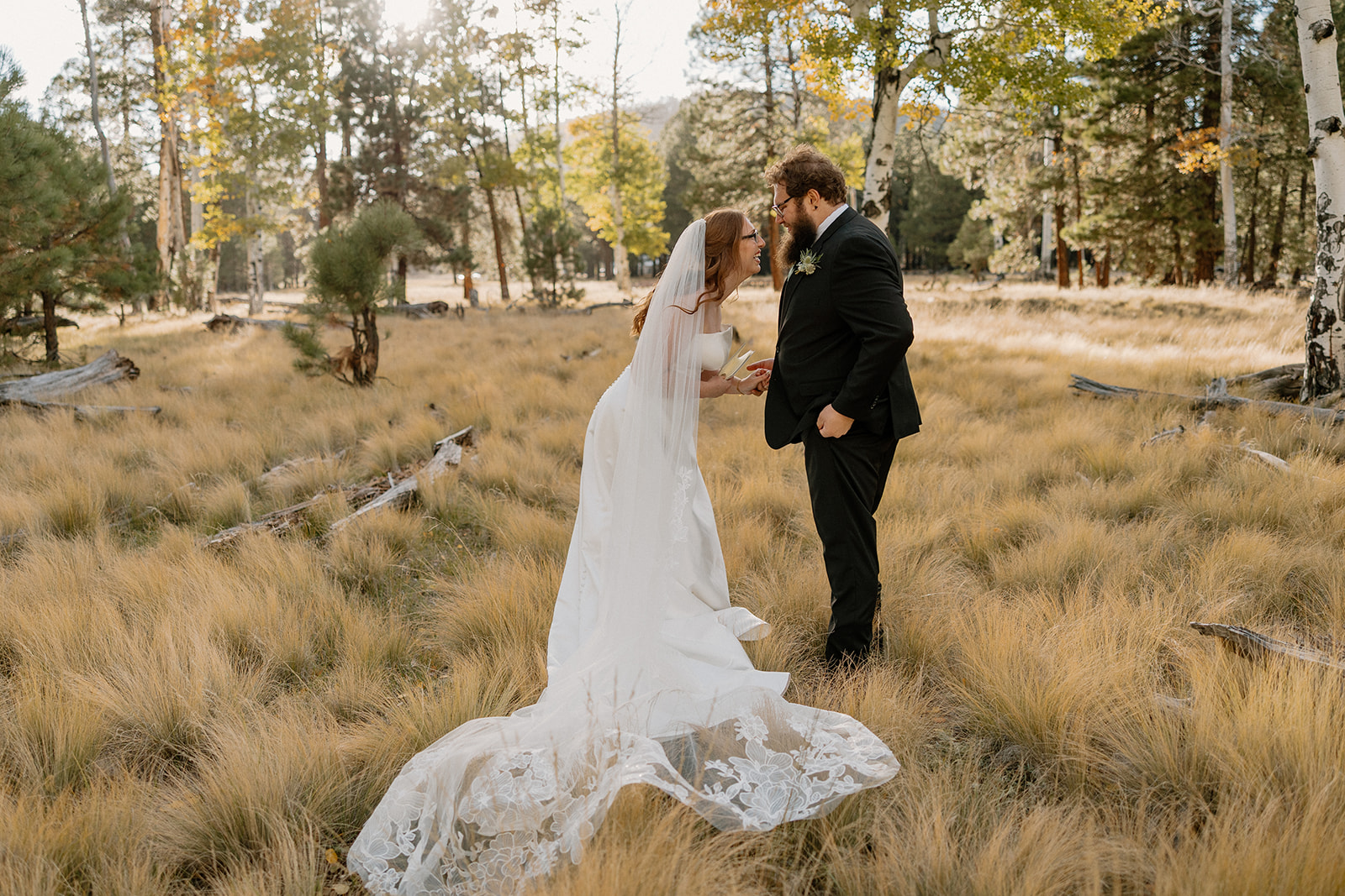 The couple shares personal vows in a quiet forest clearing, sunlight filtering through the trees at Nordic Village AZ.