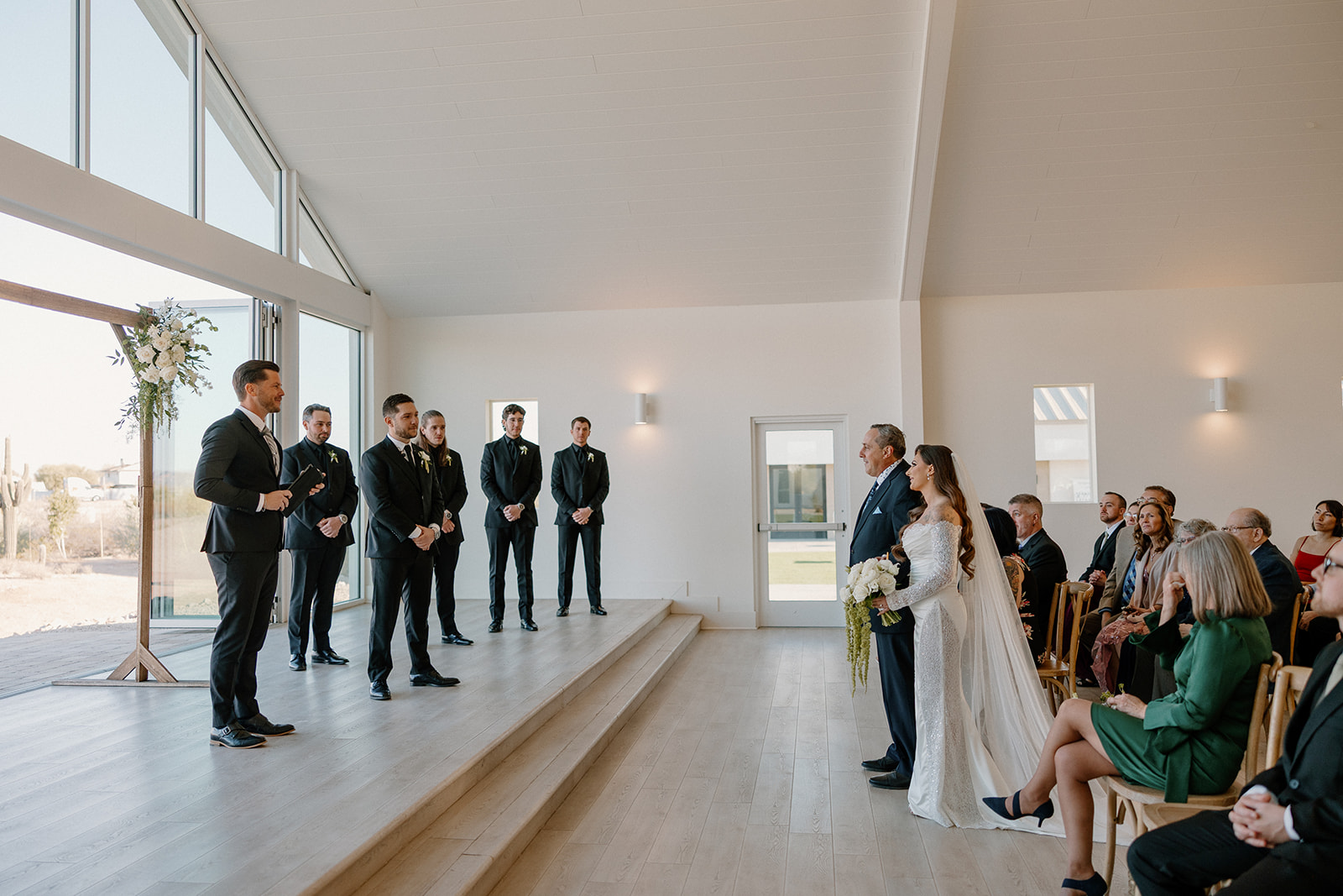 Bride and her father walk down the aisle toward the groom as the wedding party waits — an emotional milestone in any wedding planning guide.