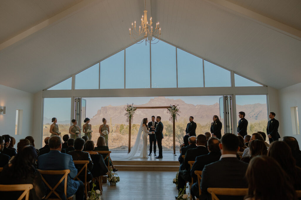 Indoor ceremony with open doors to mountain views and seated guests watching vows unfold.