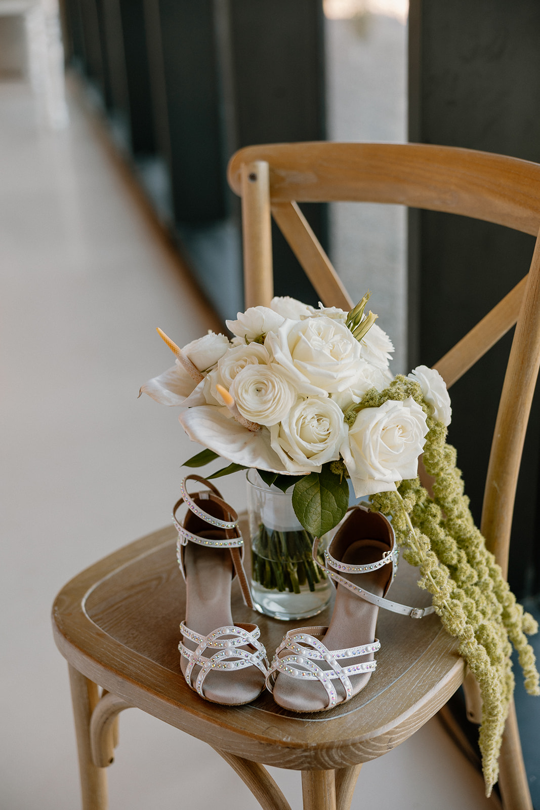 Bridal details including white rose bouquet and pearl sandals styled on a wooden chair — essential for any wedding planning guide flat lay.