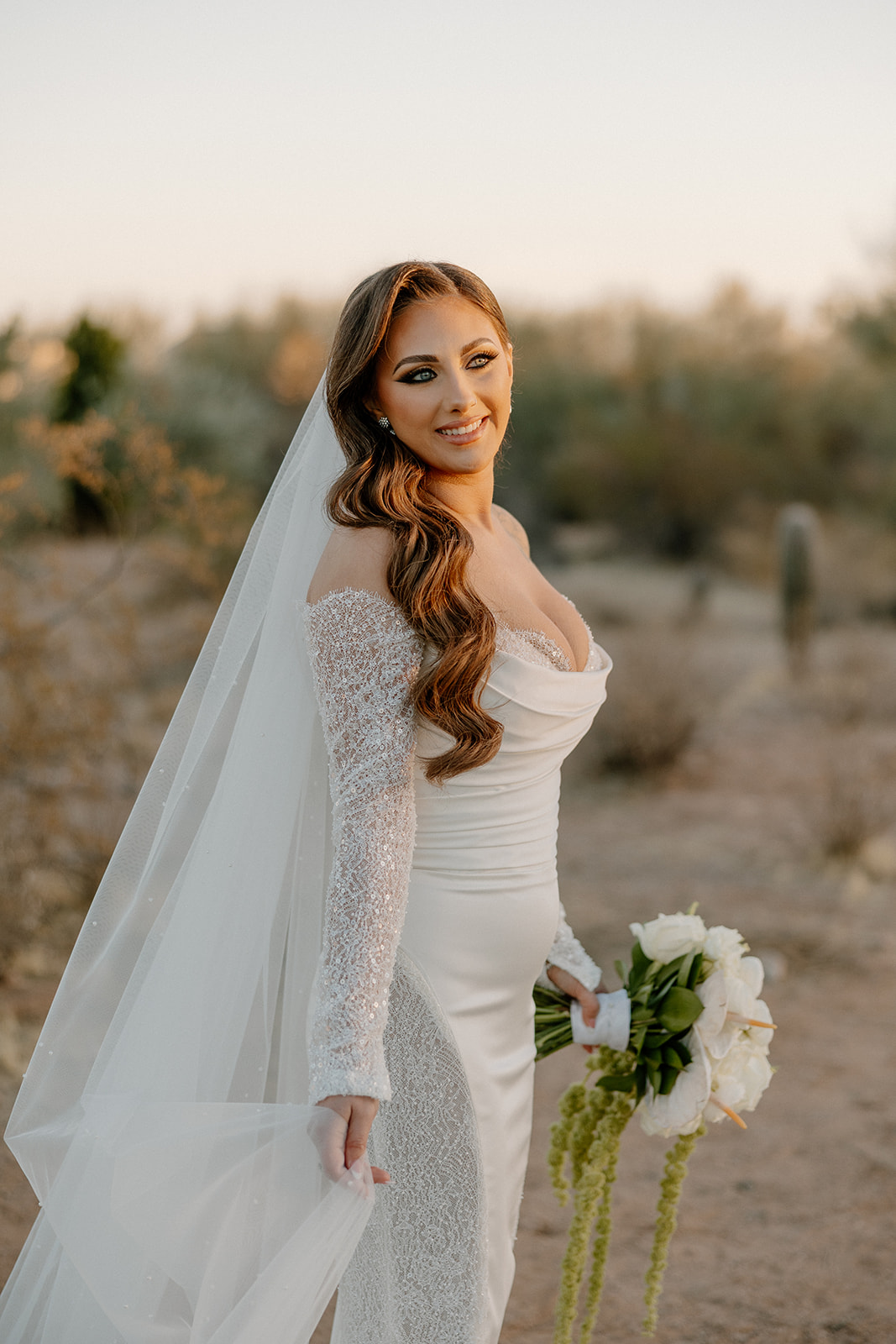Golden hour bridal portrait with long veil and textured sleeves, captured in the Arizona desert.