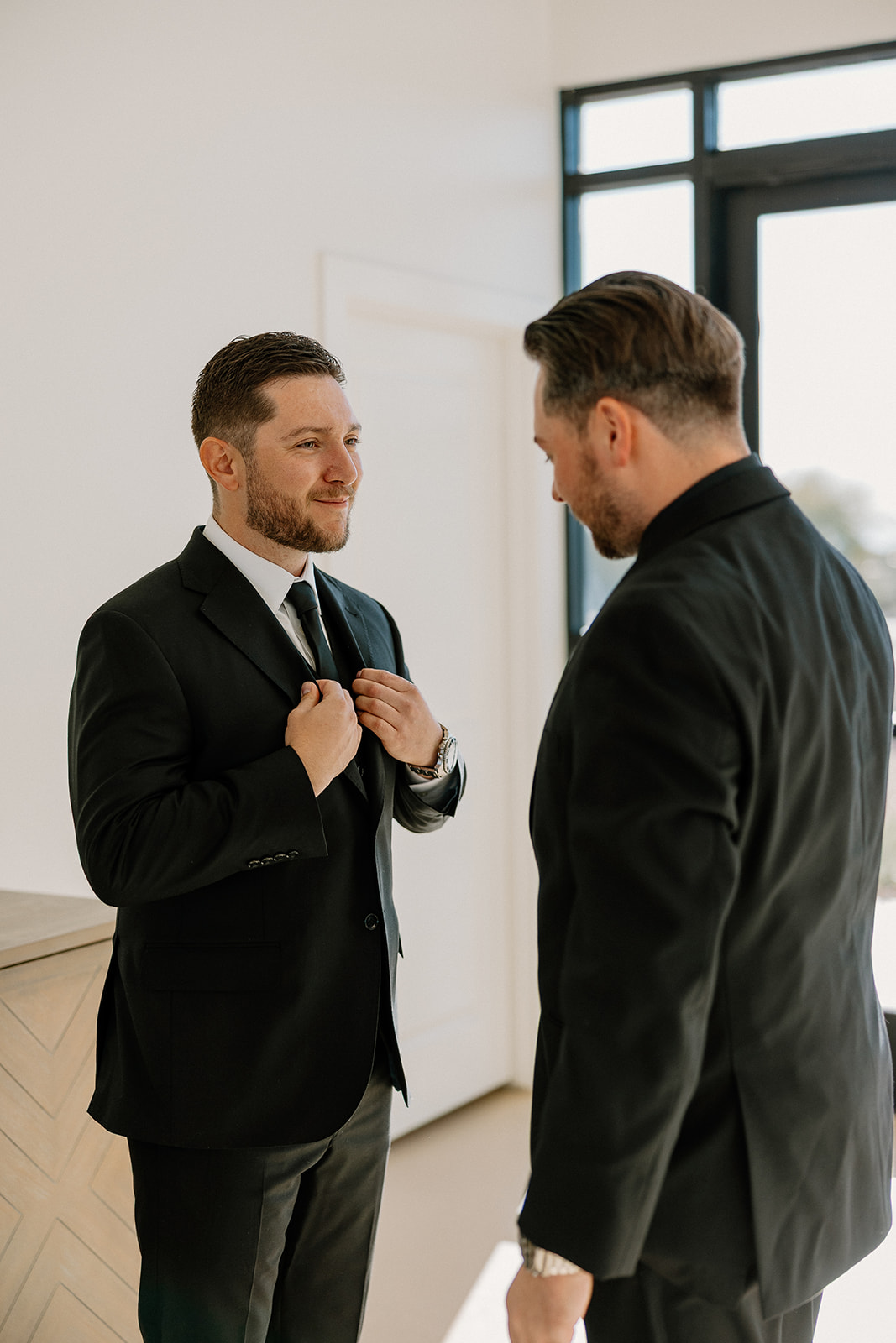 Final touch-ups before the ceremony as the groom straightens his tie with help from the best man.
