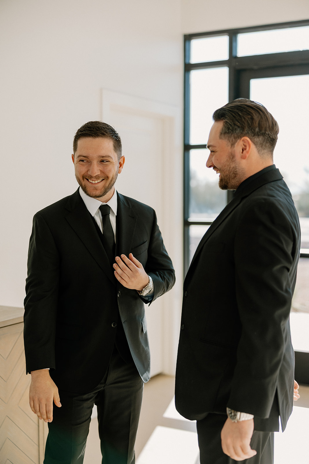 Candid shot of the groom adjusting his tie with natural light pouring in — real-life wedding planning guide moment.
