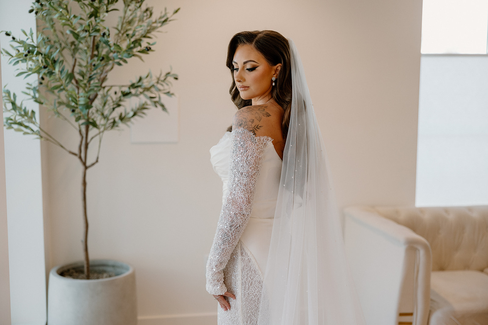 Modern bridal portrait featuring a long veil and off-the-shoulder gown in a minimalist space.