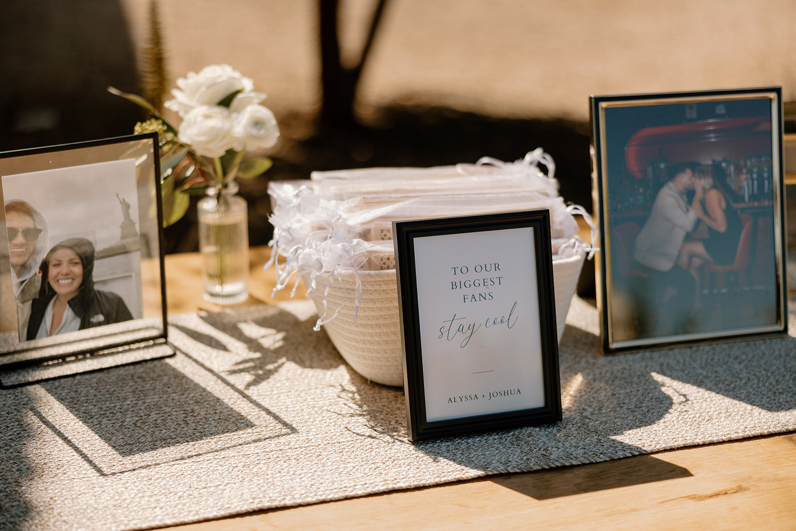 Wedding welcome table with framed photos of the couple, flowers, and a sign reading “To Our Biggest Fans, Stay Cool” at one of the most creative wedding venues in Arizona.