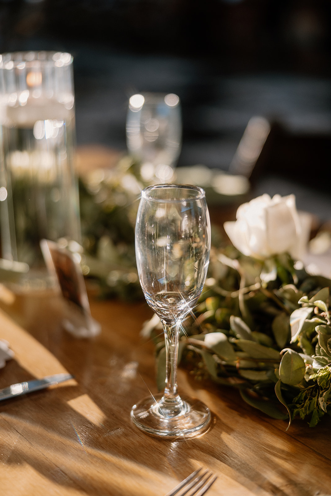 Champagne flute and soft floral details glowing in golden hour light on a reception table.