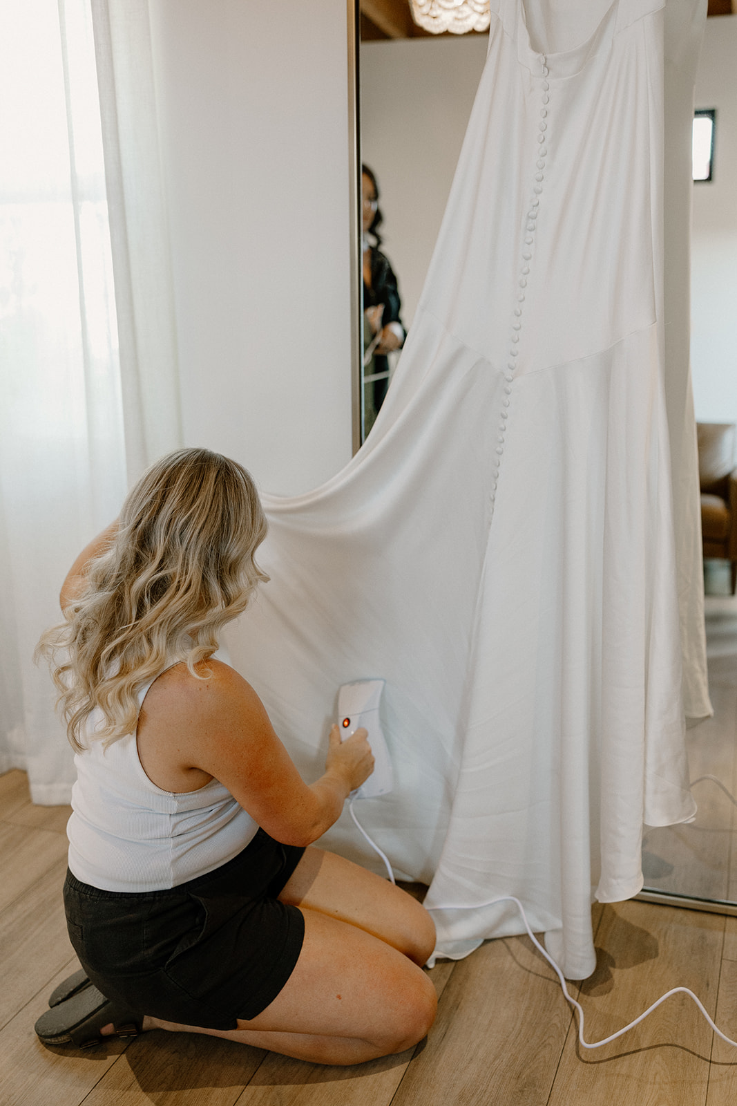 Bride steaming her wedding dress inside a desert venue suite, getting ready for her big day at one of the top wedding venues in Arizona.