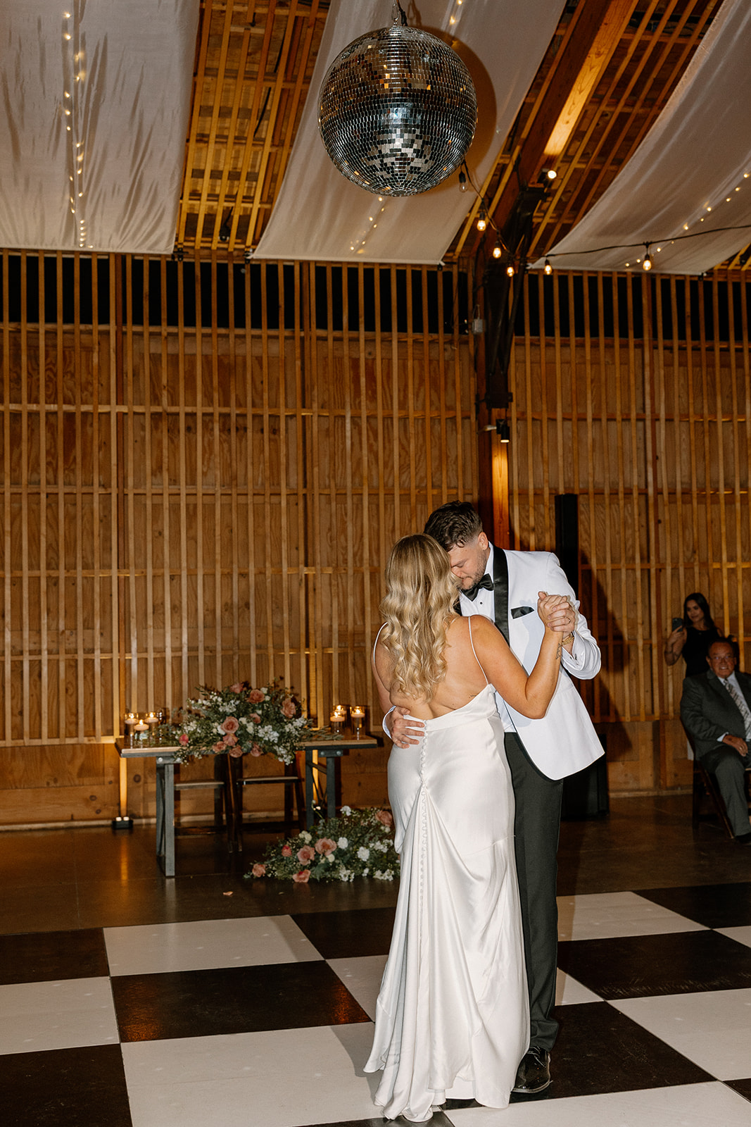 First dance under a disco ball as the couple shares a romantic moment on the checkered floor of a modern Arizona wedding venue.