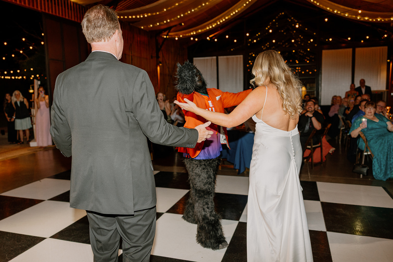 Bride dancing with her father and the Phoenix Suns mascot at a fun-filled wedding reception at a desert venue in Arizona.