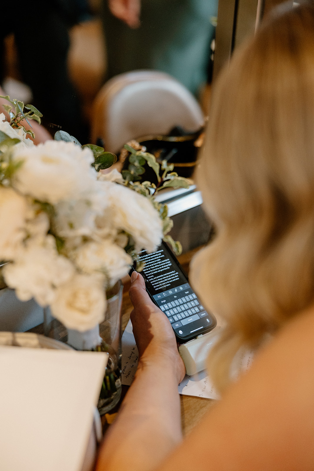 Close-up of bride reading vows on her phone next to her bouquet, a quiet and emotional moment captured before the ceremony.