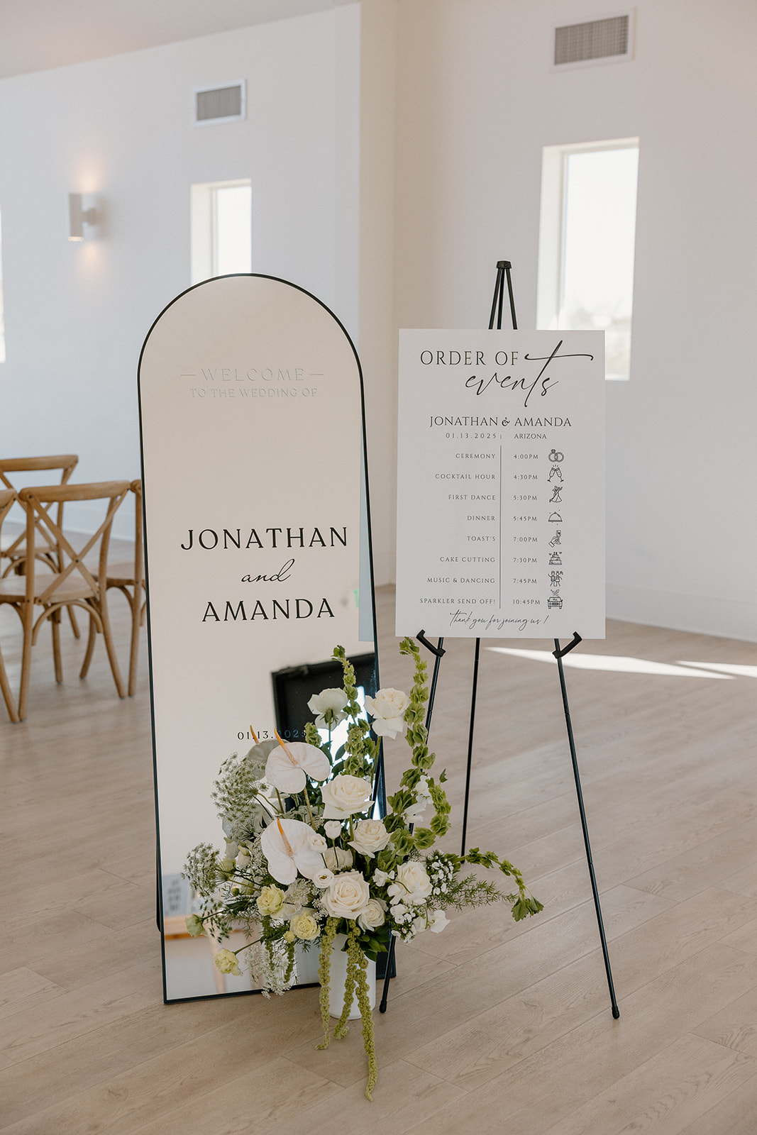 Minimalist welcome sign and order of events displayed on mirrors and easels, styled with modern florals inside the ceremony space.
