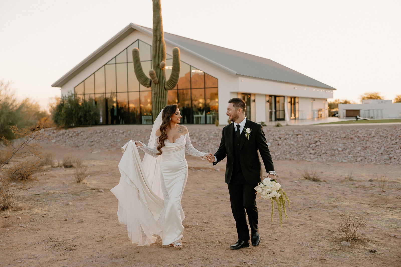 Bride and groom joyfully walk through a sparkler tunnel, surrounded by friends celebrating under the night sky.