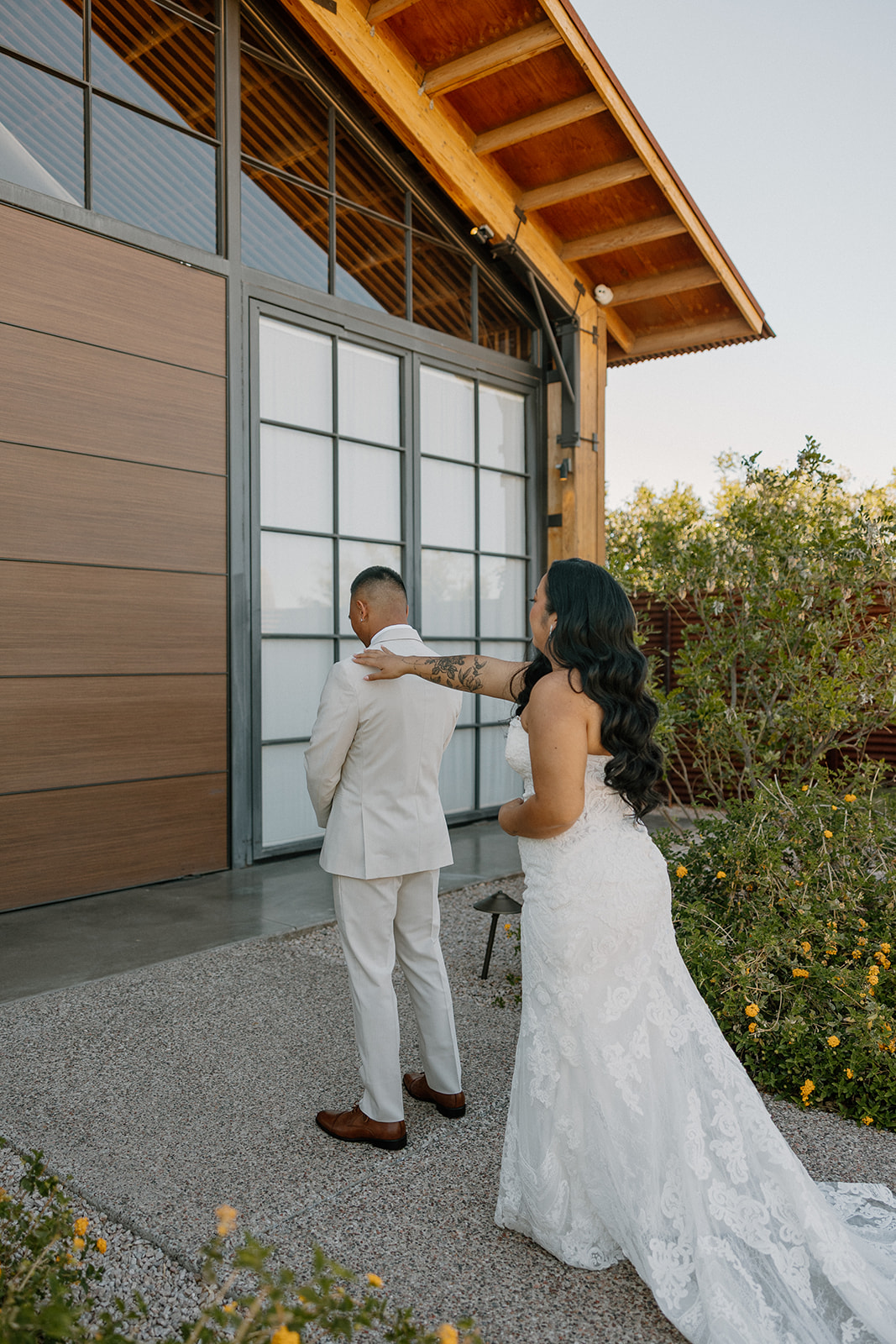 Bride reaching out to tap the groom on the shoulder for their first look outside The Paseo wedding venue.