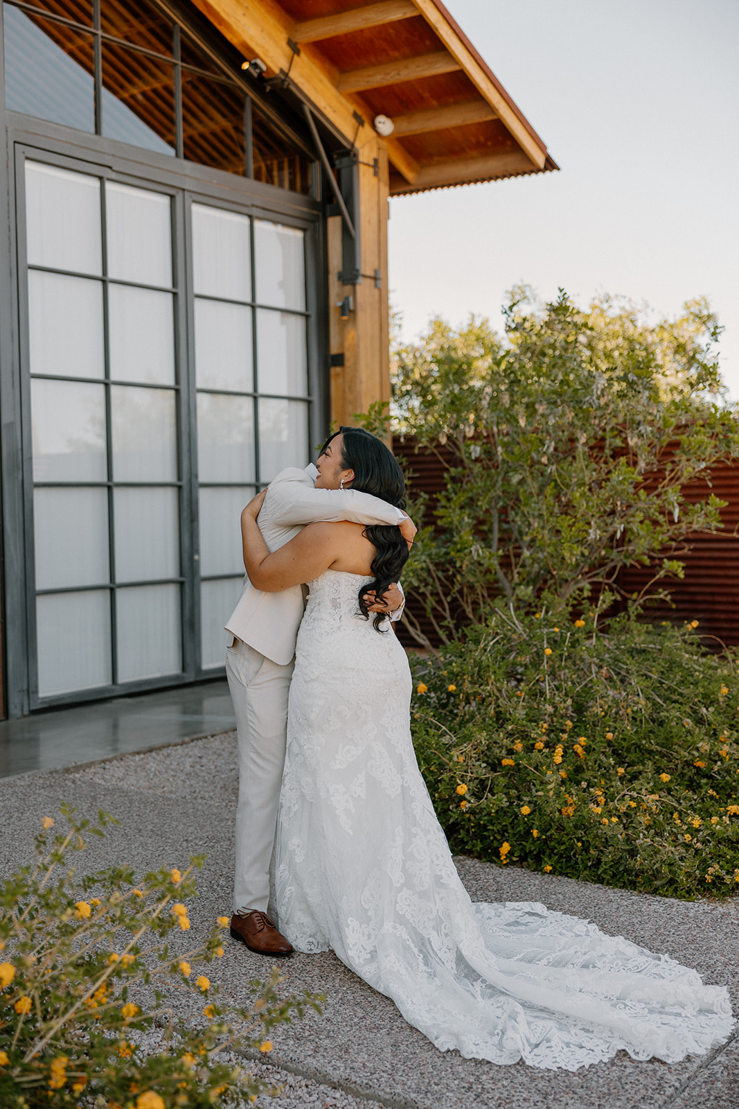 Bride and groom hugging after their first look, surrounded by golden desert blooms at The Paseo wedding venue.