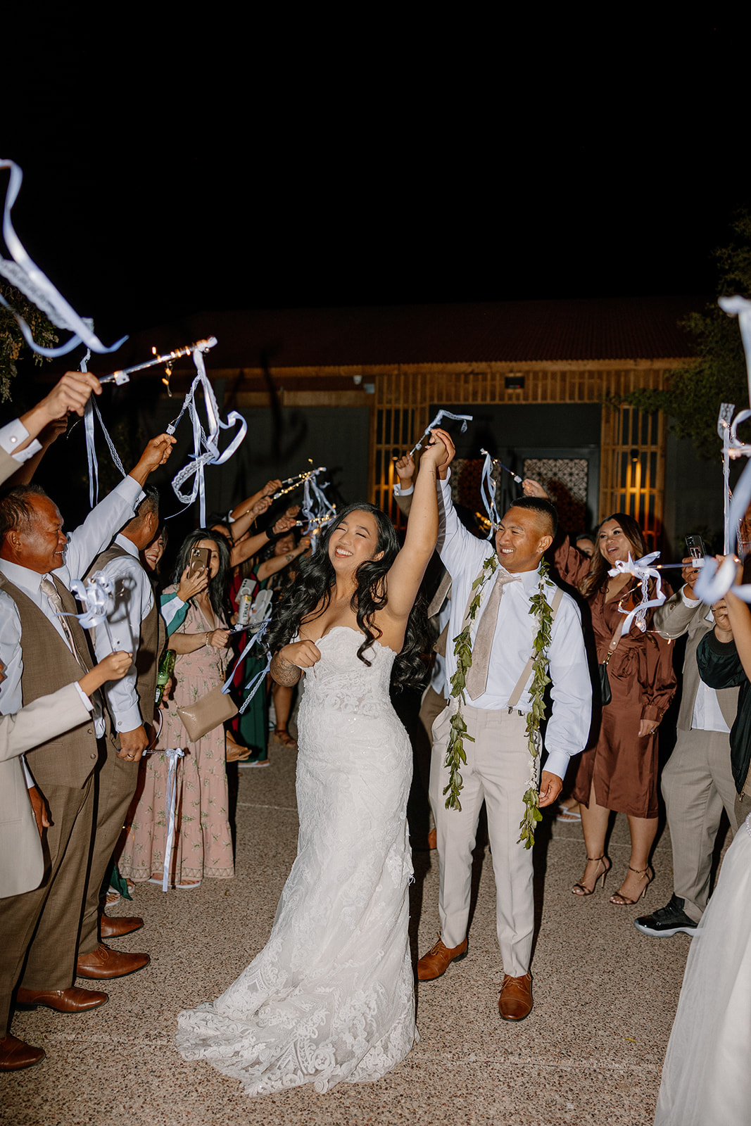 Ribbon wand send-off at The Paseo wedding, with the couple dancing through their cheering guests under the night sky.